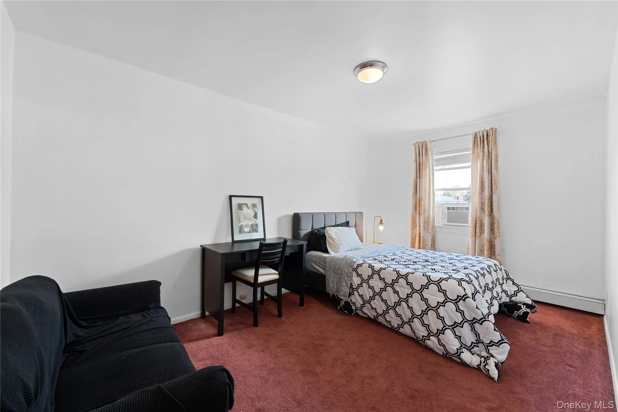 Carpeted bedroom featuring baseboard heating and baseboards Carpeted bedroom featuring baseboard heating and baseboards