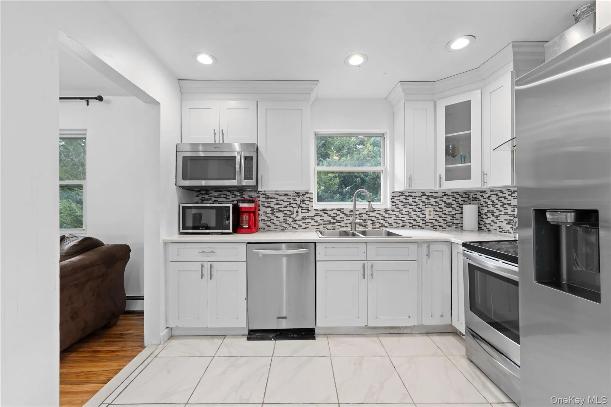 Kitchen with stainless steel appliances, white cabinets, glass insert cabinets, backsplash, and recessed lighting Kitchen with stainless steel appliances, white cabinets, glass insert cabinets, backsplash, and recessed lighting