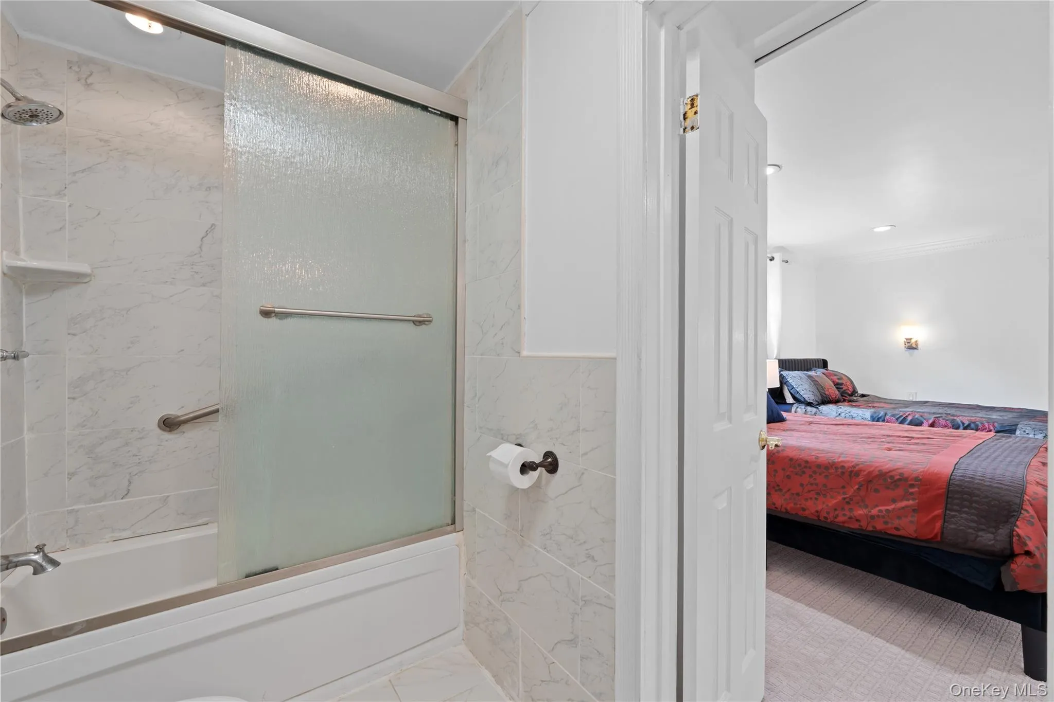 Ensuite bathroom featuring bath / shower combo with glass door, light marble finish floors, and recessed lighting Ensuite bathroom featuring bath / shower combo with glass door, light marble finish floors, and recessed lighting