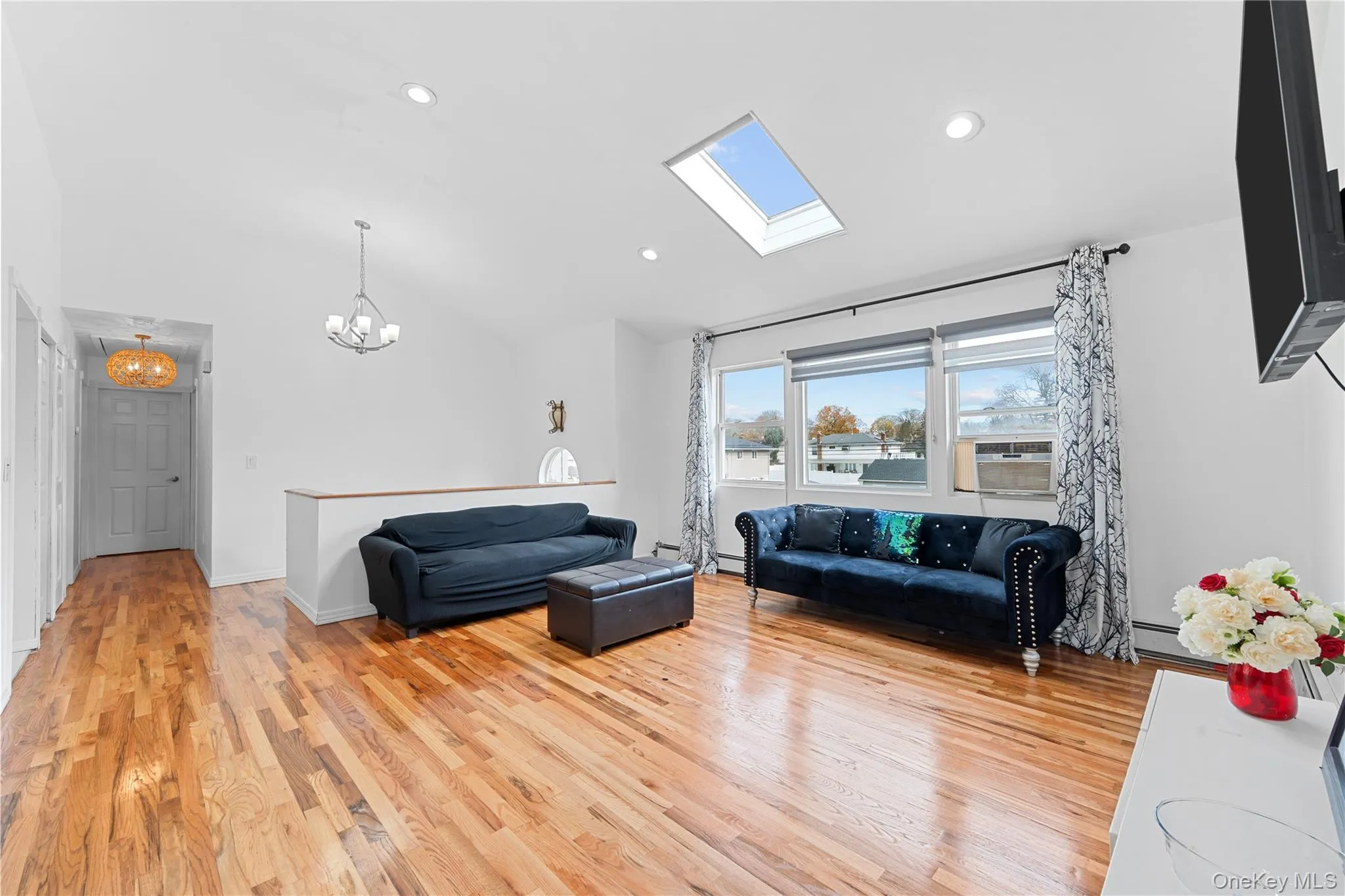 Living room featuring a skylight, light wood finished floors, lofted ceiling, cooling unit, and recessed lighting Living room featuring a skylight, light wood finished floors, lofted ceiling, cooling unit, and recessed lighting