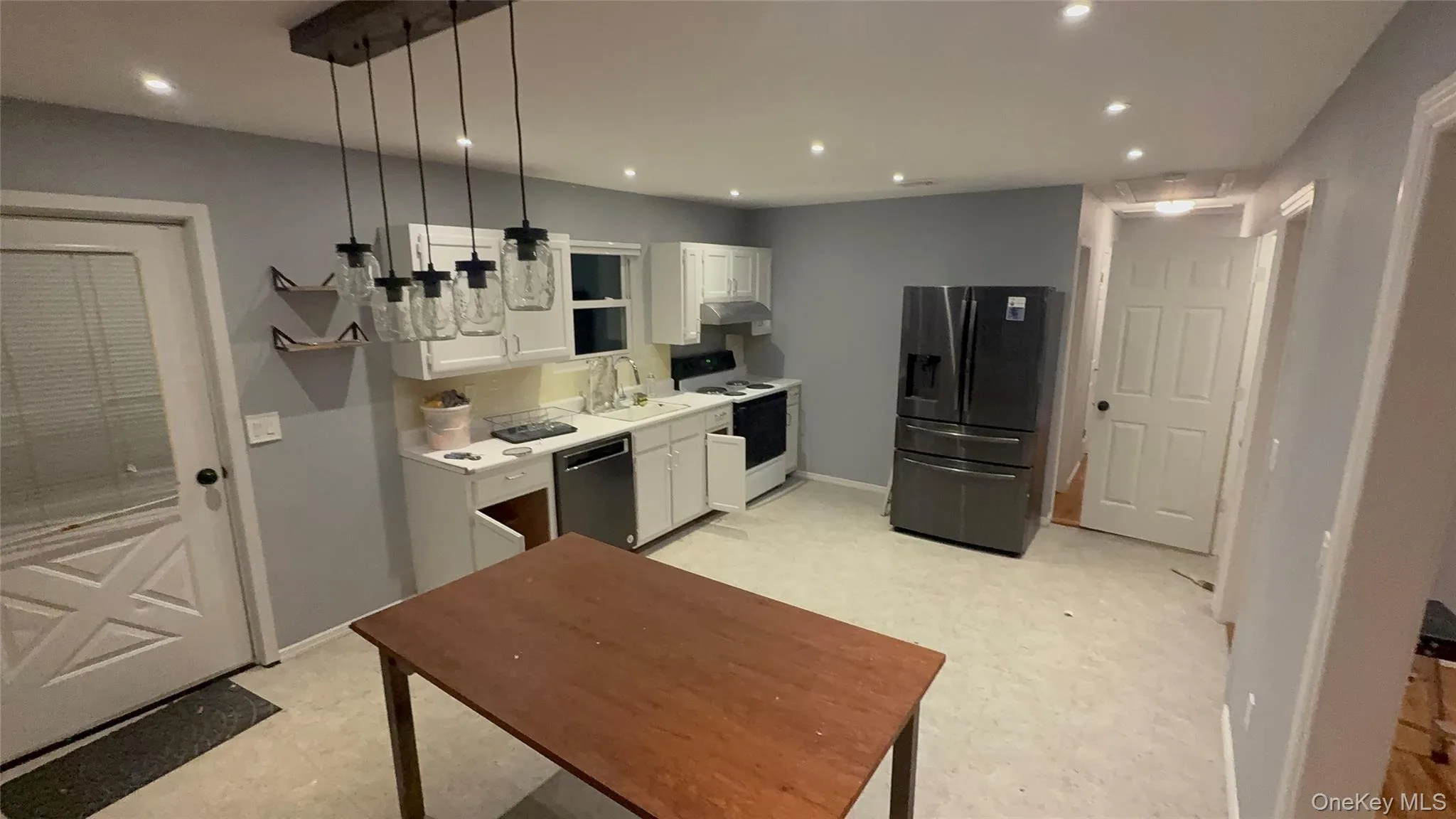 Kitchen with white cabinetry, light countertops, stainless steel fridge with ice dispenser, electric stove, and light floors Kitchen with white cabinetry, light countertops, stainless steel fridge with ice dispenser, electric stove, and light floors