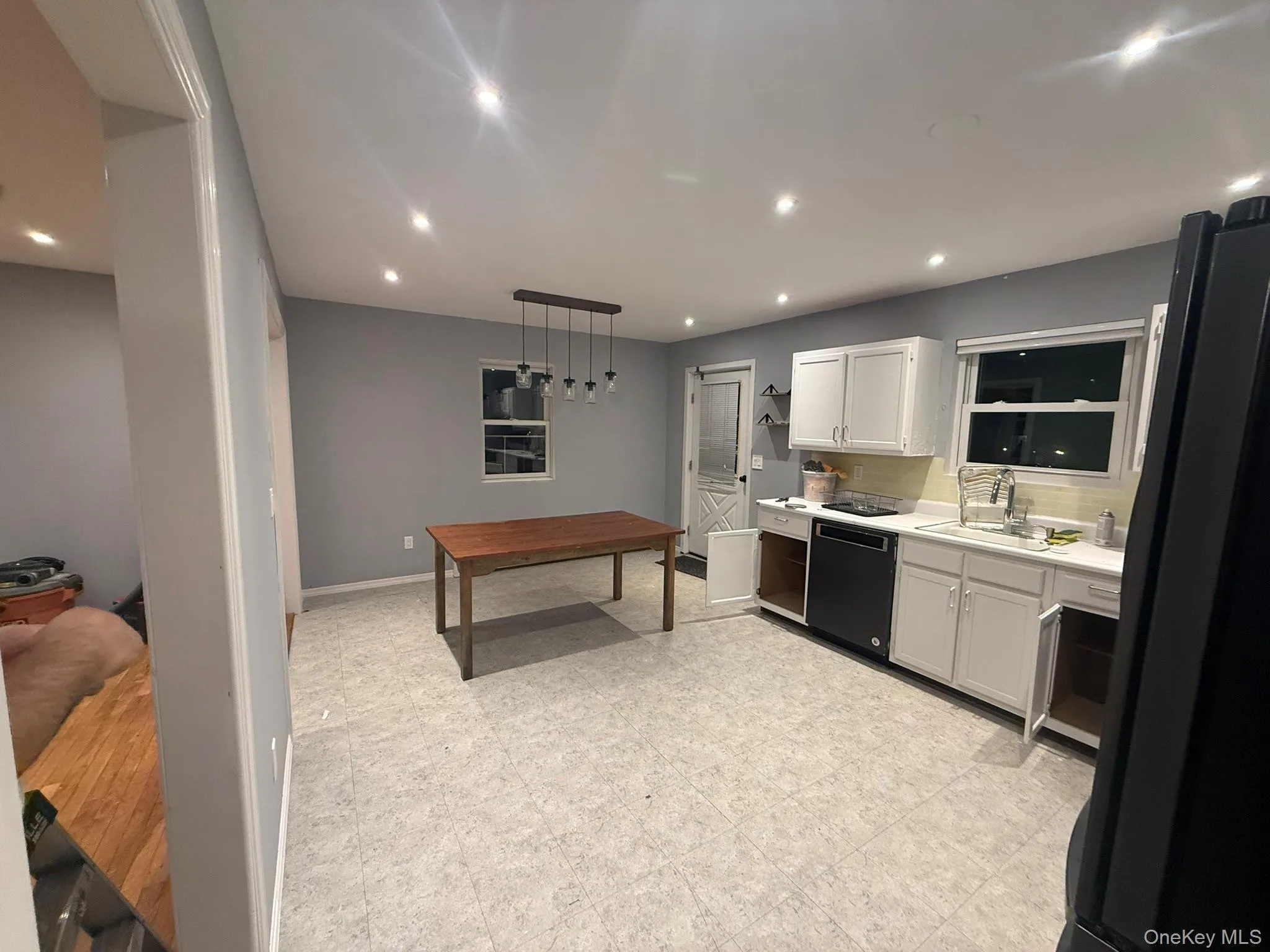 Kitchen featuring pendant lighting, light countertops, black appliances, recessed lighting, and white cabinetry Kitchen featuring pendant lighting, light countertops, black appliances, recessed lighting, and white cabinetry