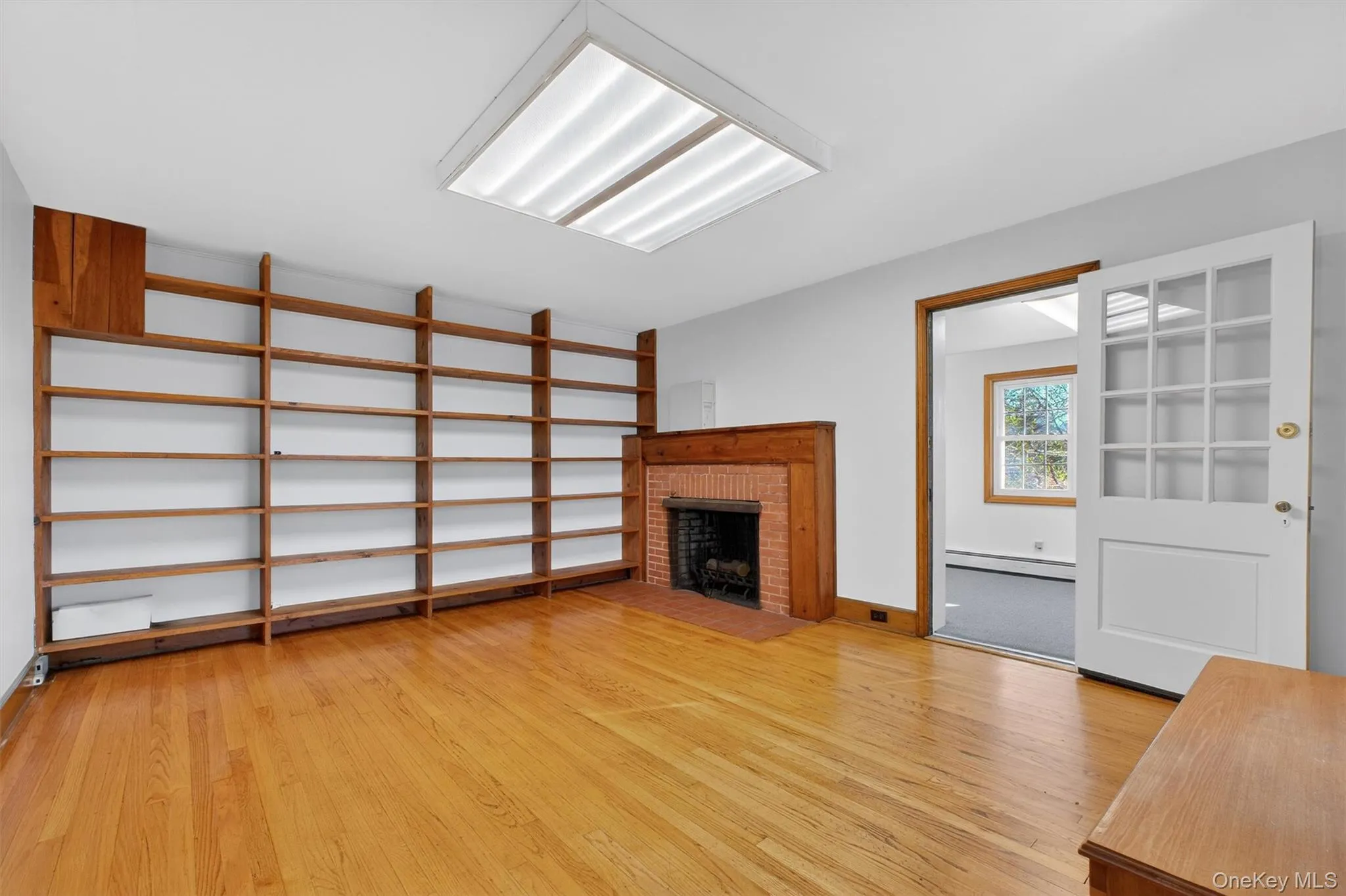 Unfurnished living room with a fireplace, light wood-style floors, and baseboard heating Unfurnished living room with a fireplace, light wood-style floors, and baseboard heating