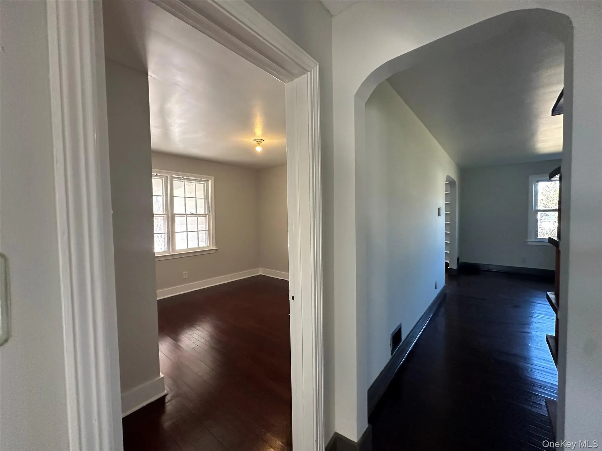 Corridor with arched walkways, dark wood-type flooring, and healthy amount of natural light Corridor with arched walkways, dark wood-type flooring, and healthy amount of natural light