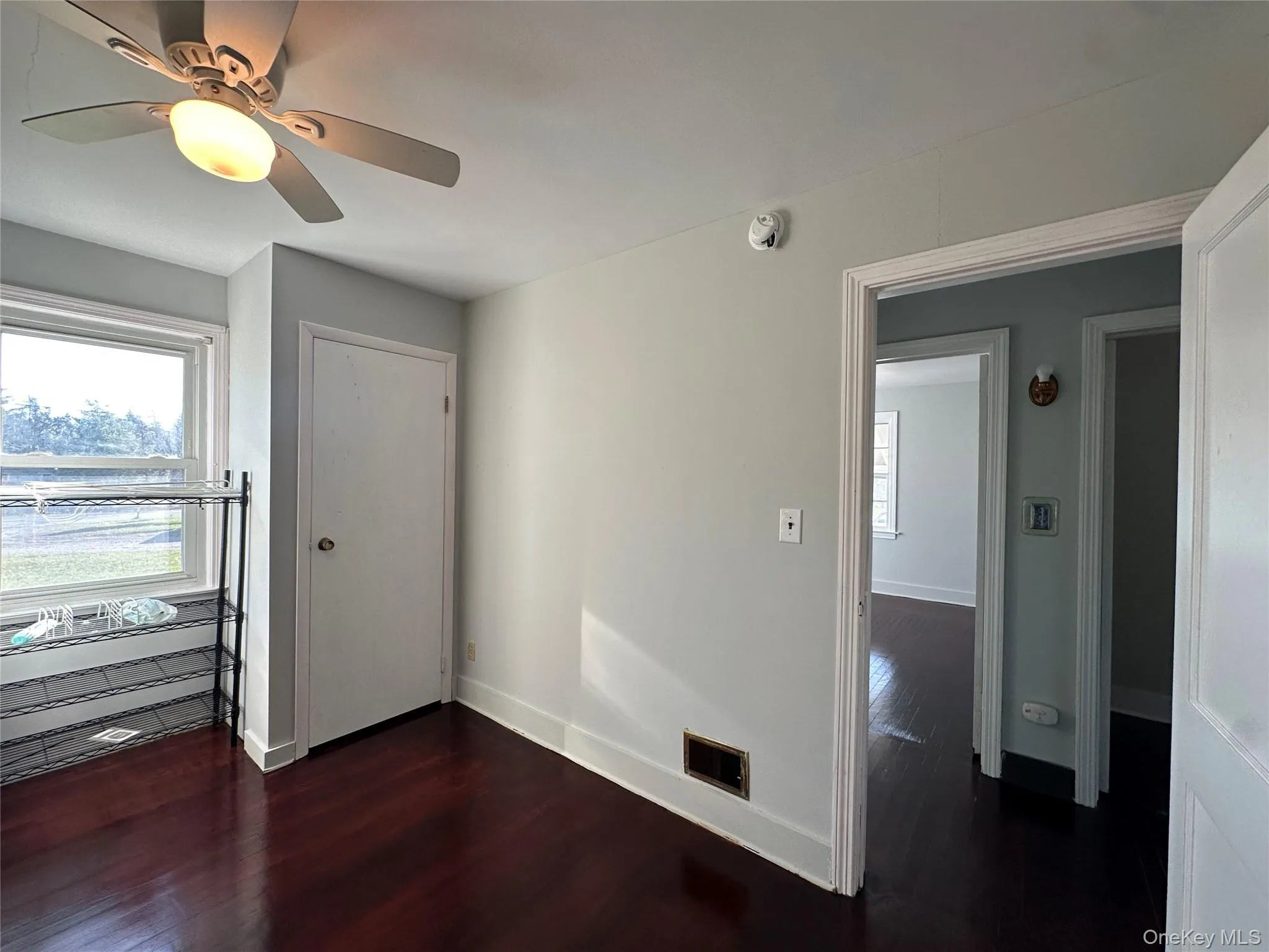 Unfurnished bedroom with dark wood finished floors, multiple windows, and a ceiling fan Unfurnished bedroom with dark wood finished floors, multiple windows, and a ceiling fan