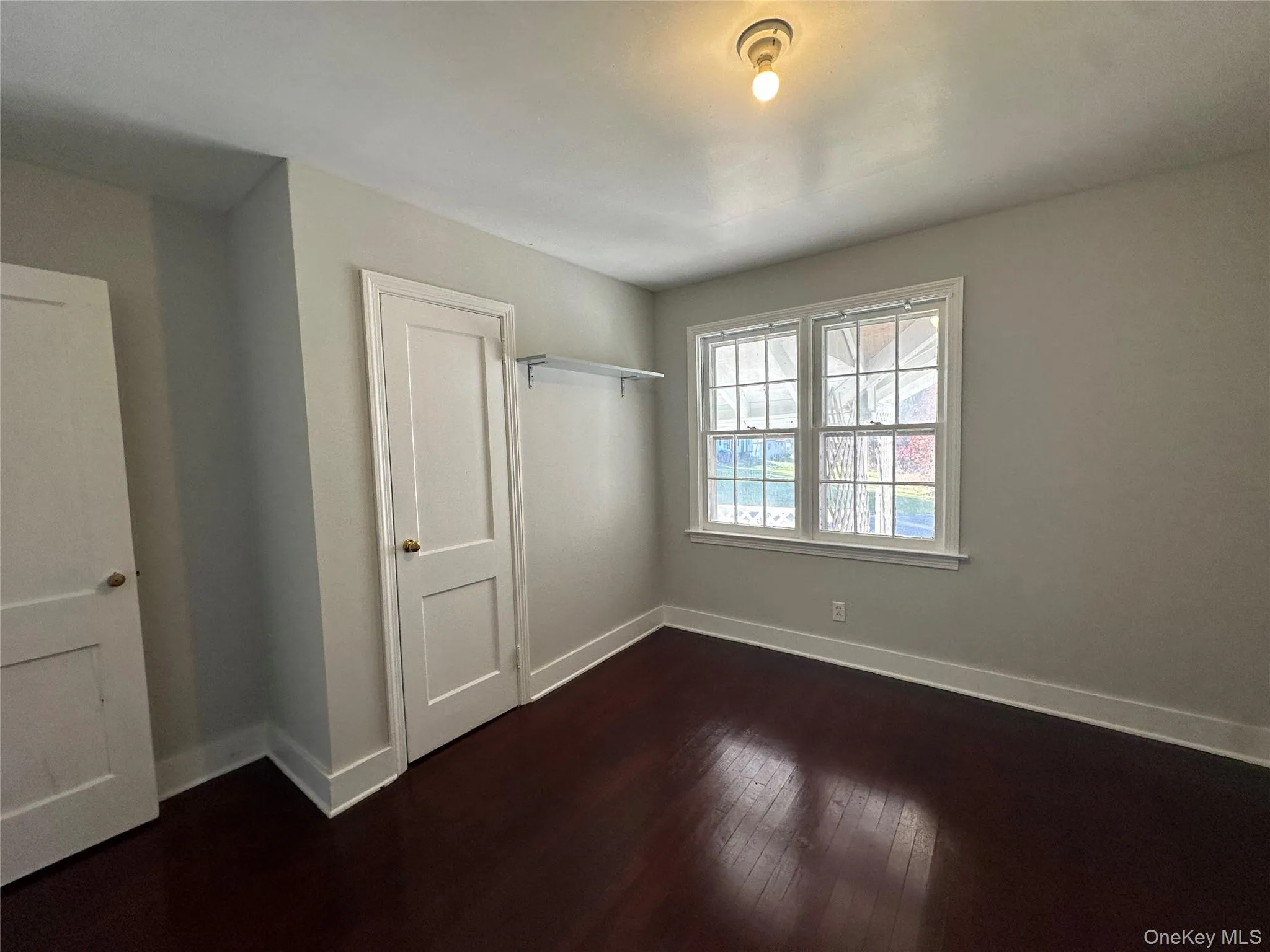 Unfurnished bedroom featuring dark wood-style floors and a closet Unfurnished bedroom featuring dark wood-style floors and a closet