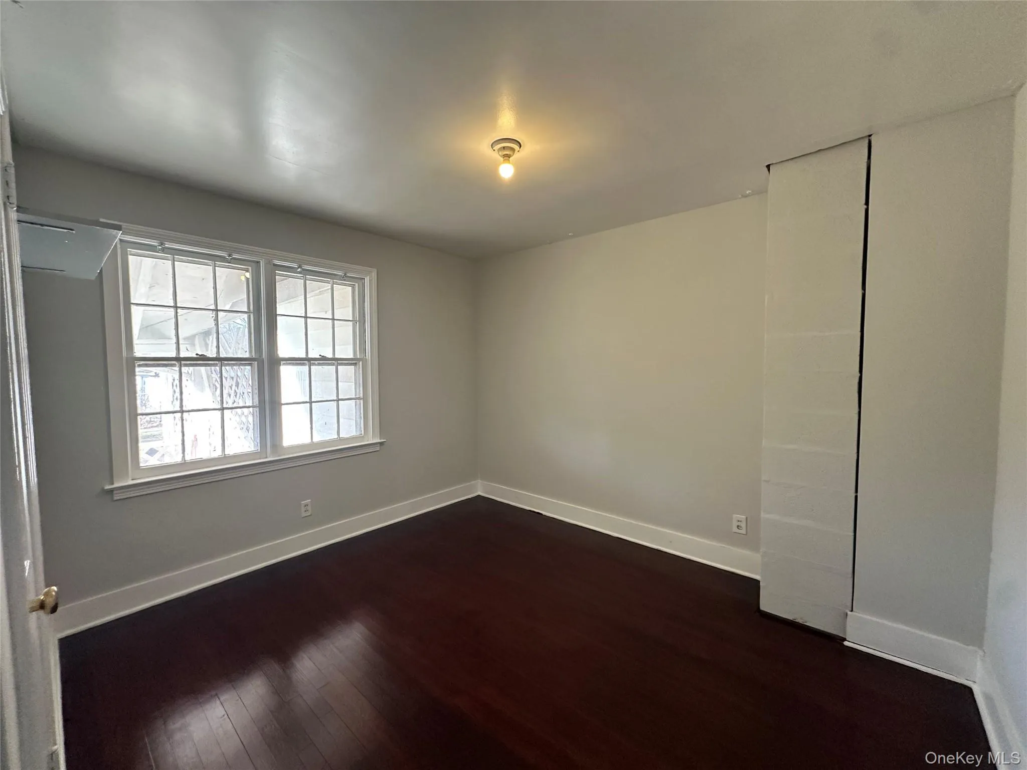 Unfurnished room with dark wood finished floors and baseboards Unfurnished room with dark wood finished floors and baseboards