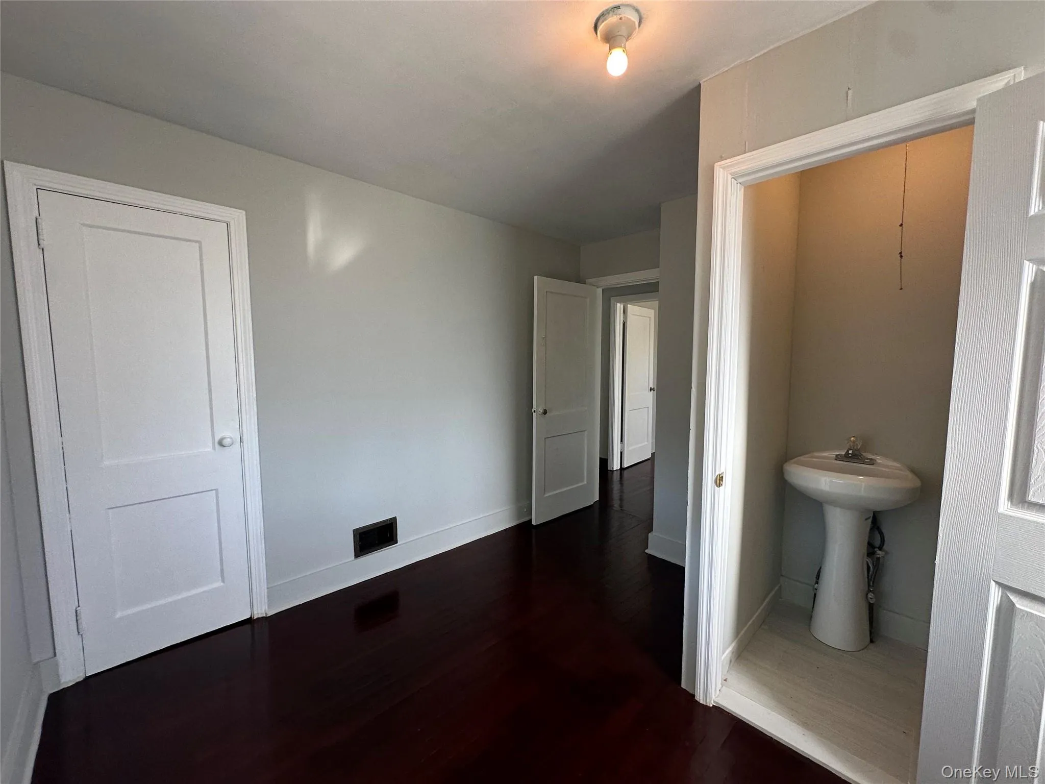 Unfurnished bedroom featuring dark wood-type flooring and baseboards Unfurnished bedroom featuring dark wood-type flooring and baseboards