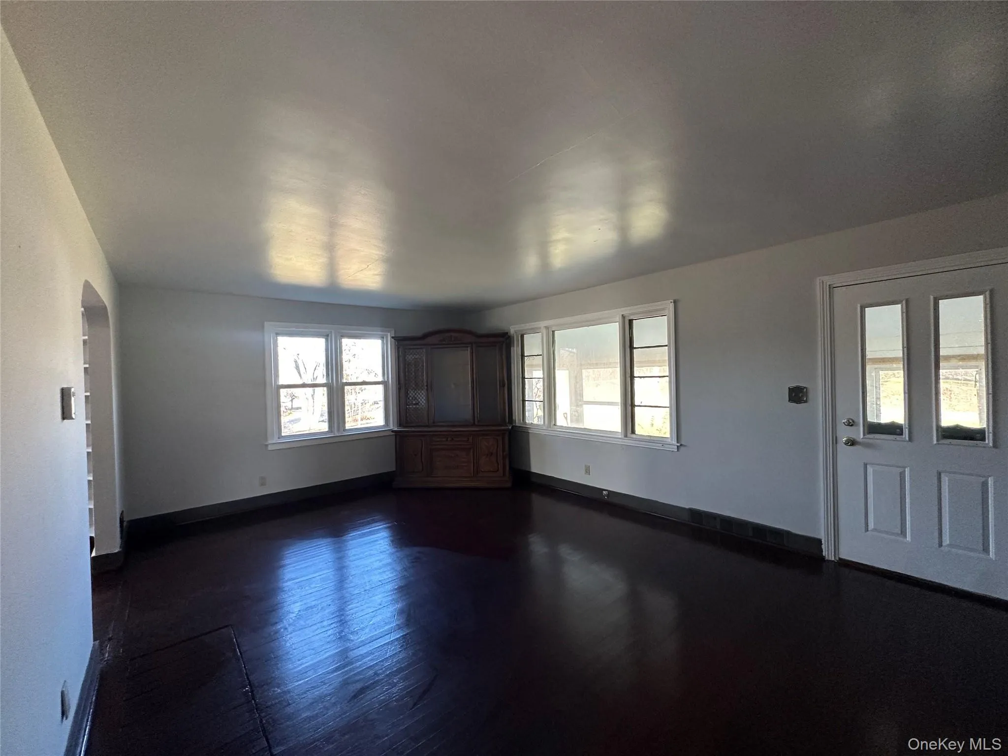 Unfurnished living room with arched walkways and dark wood-type flooring Unfurnished living room with arched walkways and dark wood-type flooring