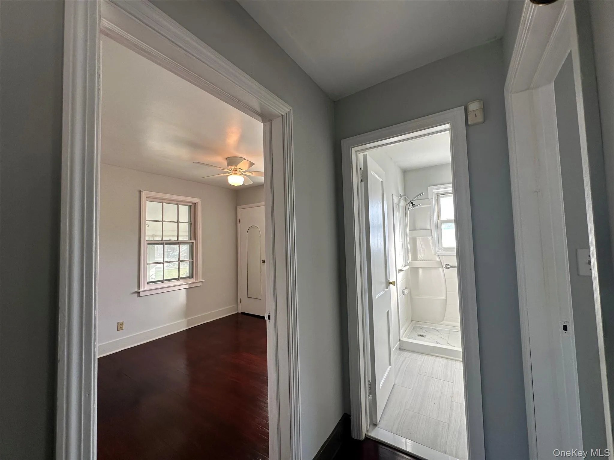 Hallway featuring baseboards and dark wood-style flooring Hallway featuring baseboards and dark wood-style flooring
