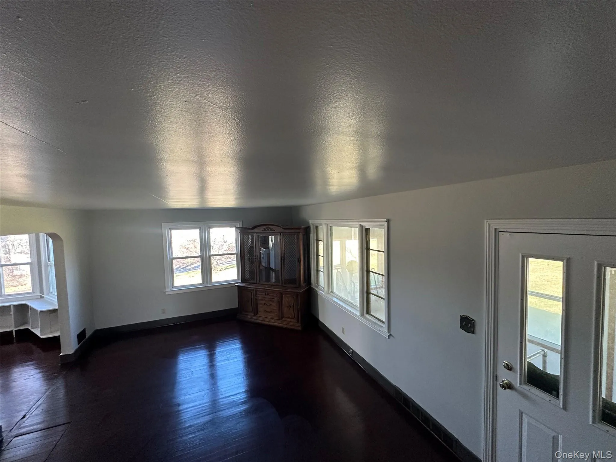 Foyer entrance featuring arched walkways, a textured ceiling, and dark wood-style floors Foyer entrance featuring arched walkways, a textured ceiling, and dark wood-style floors