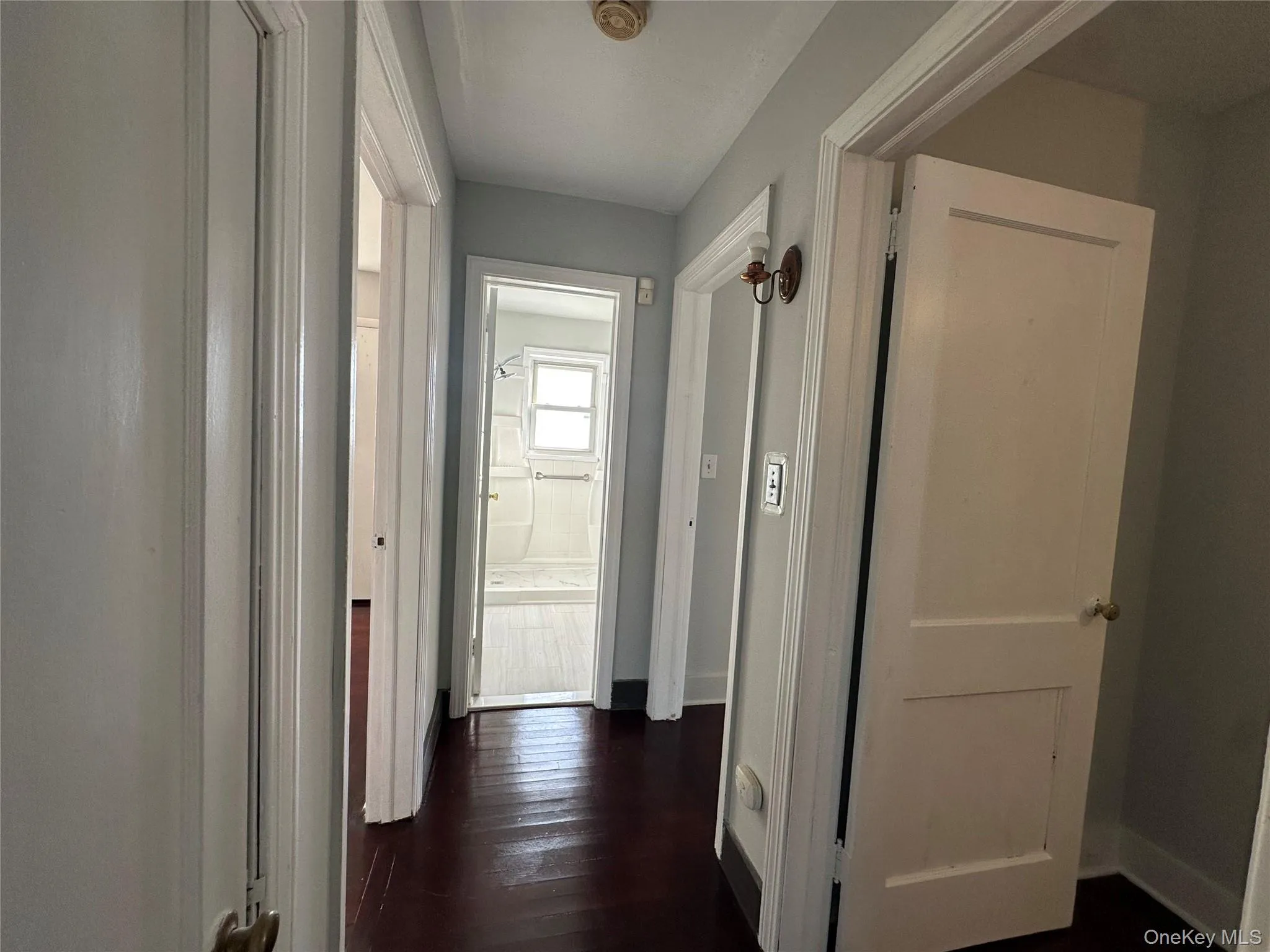 Hallway featuring dark wood-style flooring and baseboards Hallway featuring dark wood-style flooring and baseboards