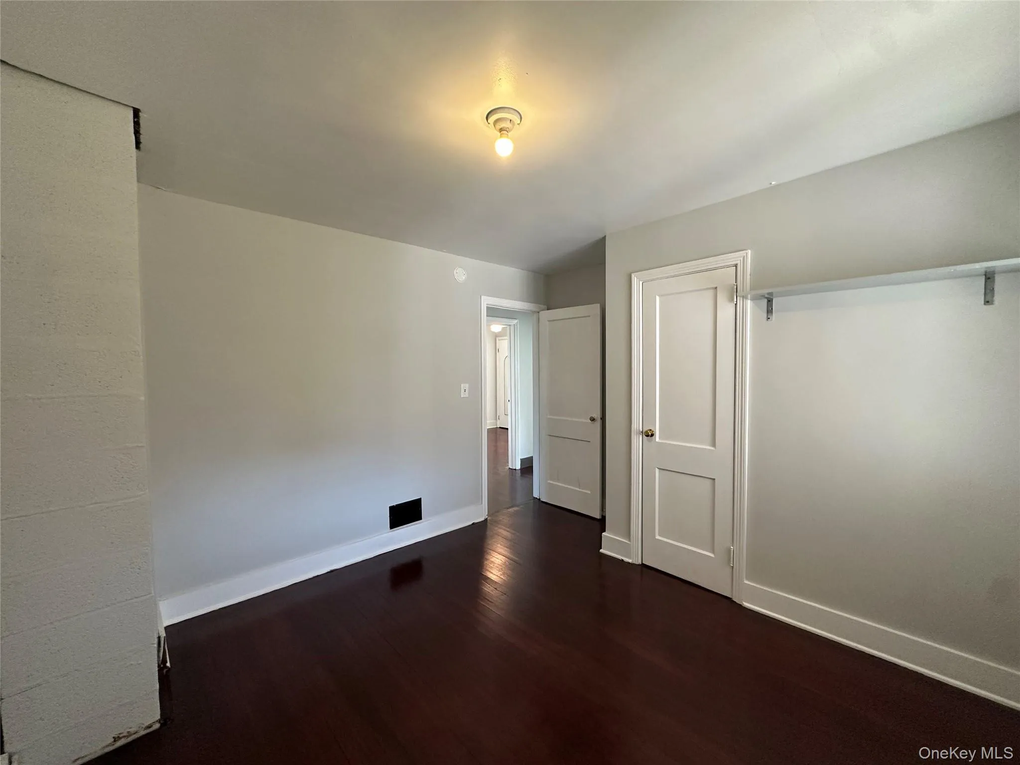 Unfurnished bedroom with dark wood-style flooring and a closet Unfurnished bedroom with dark wood-style flooring and a closet