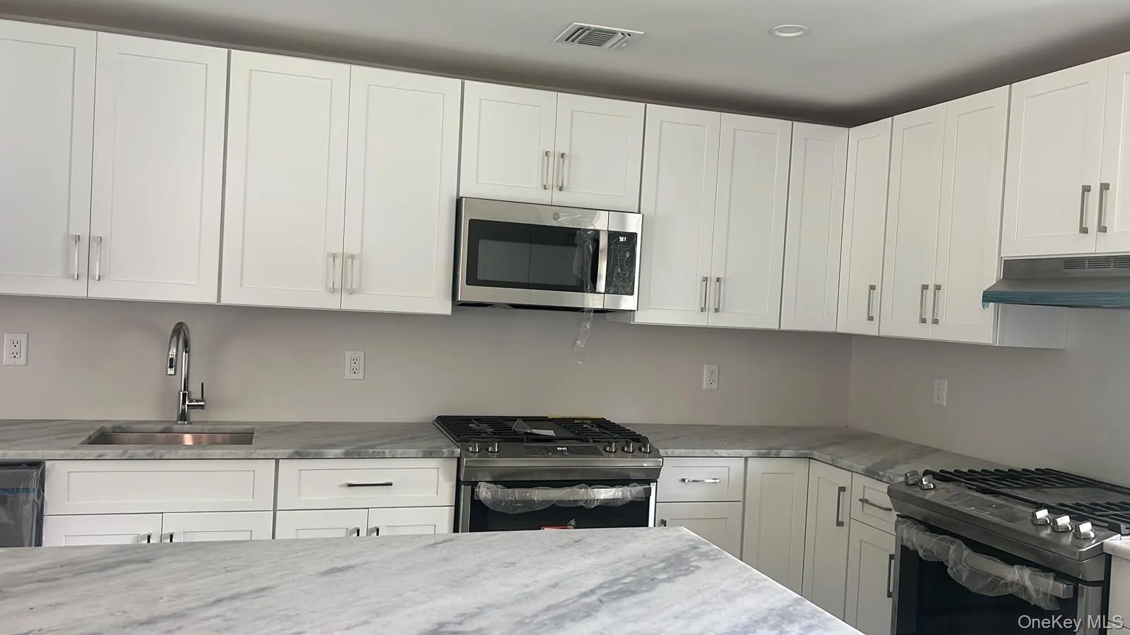 Kitchen with stainless steel appliances, white cabinets, and light stone counters Kitchen with stainless steel appliances, white cabinets, and light stone counters
