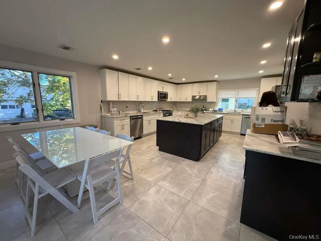 Kitchen featuring light stone countertops, a center island, recessed lighting, white cabinets, and stainless steel appliances Kitchen featuring light stone countertops, a center island, recessed lighting, white cabinets, and stainless steel appliances