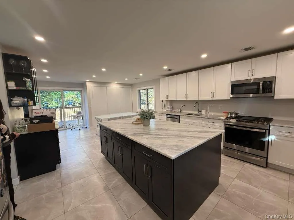 Kitchen featuring stainless steel appliances, dark cabinets, recessed lighting, white cabinets, and a center island Kitchen featuring stainless steel appliances, dark cabinets, recessed lighting, white cabinets, and a center island