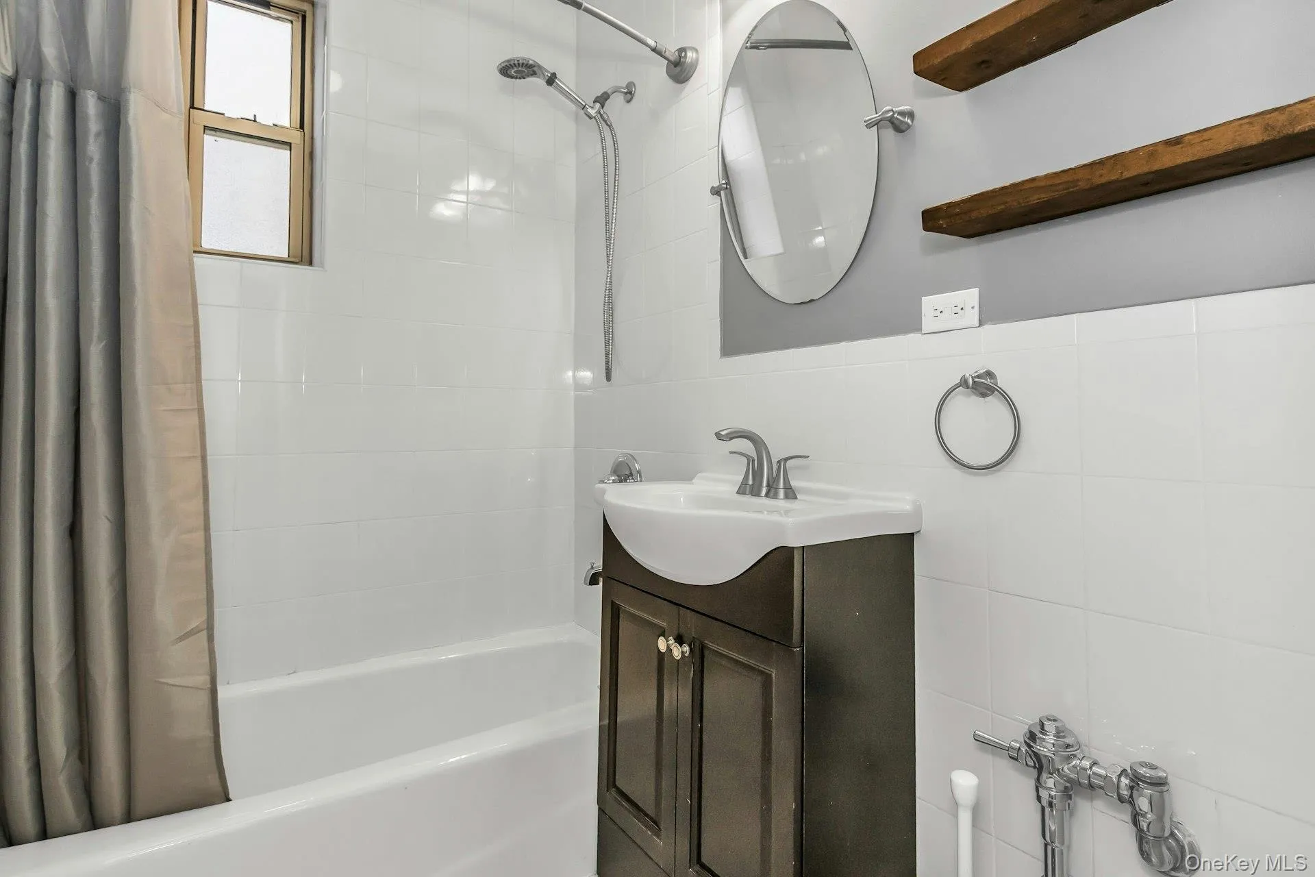 Bathroom with vanity, tile walls, and shower / tub combo with curtain Bathroom with vanity, tile walls, and shower / tub combo with curtain