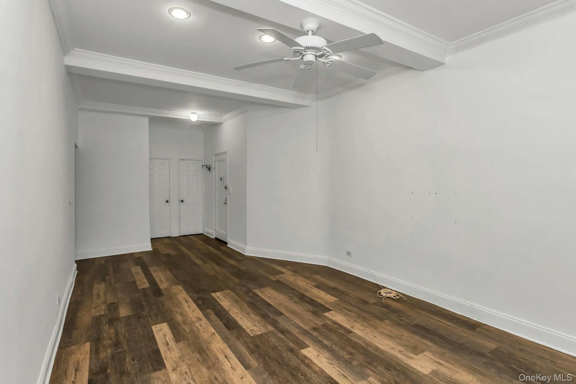 Unfurnished room with ornamental molding, dark wood-style floors, beam ceiling, and ceiling fan Unfurnished room with ornamental molding, dark wood-style floors, beam ceiling, and ceiling fan