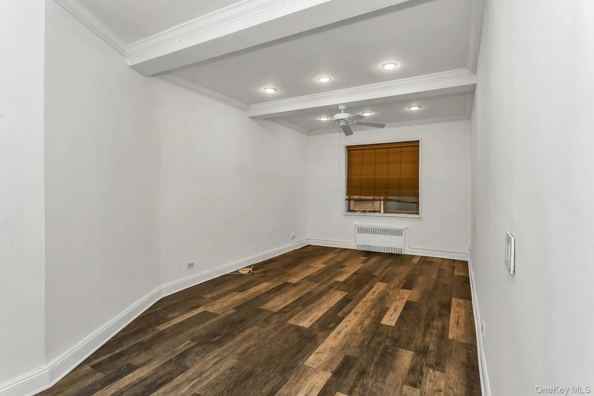Spare room with dark wood finished floors, ceiling fan, radiator heating unit, crown molding, and recessed lighting Spare room with dark wood finished floors, ceiling fan, radiator heating unit, crown molding, and recessed lighting