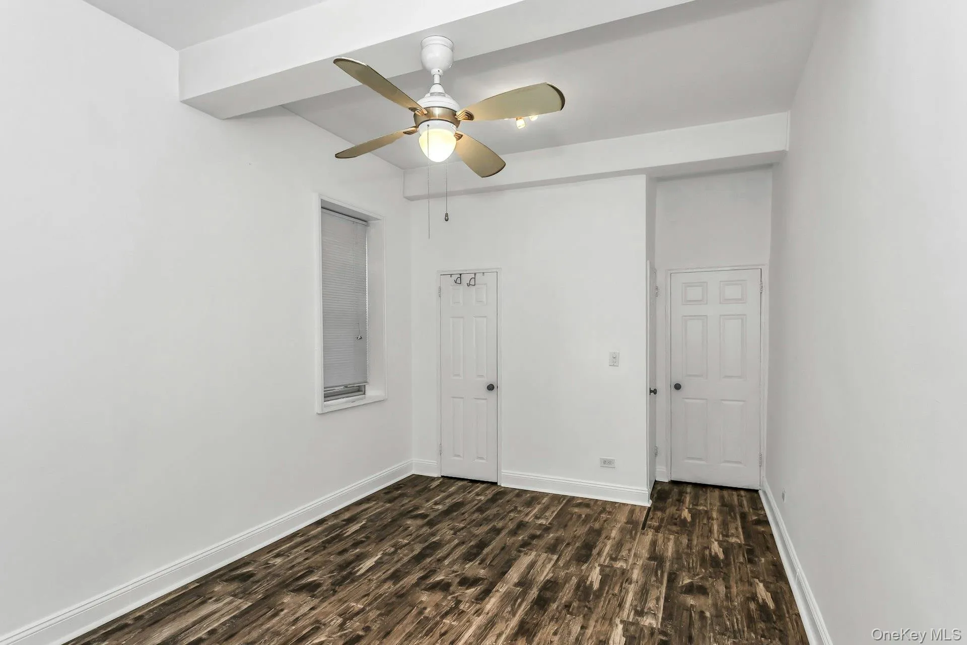 Spare room featuring dark wood-style flooring and ceiling fan Spare room featuring dark wood-style flooring and ceiling fan