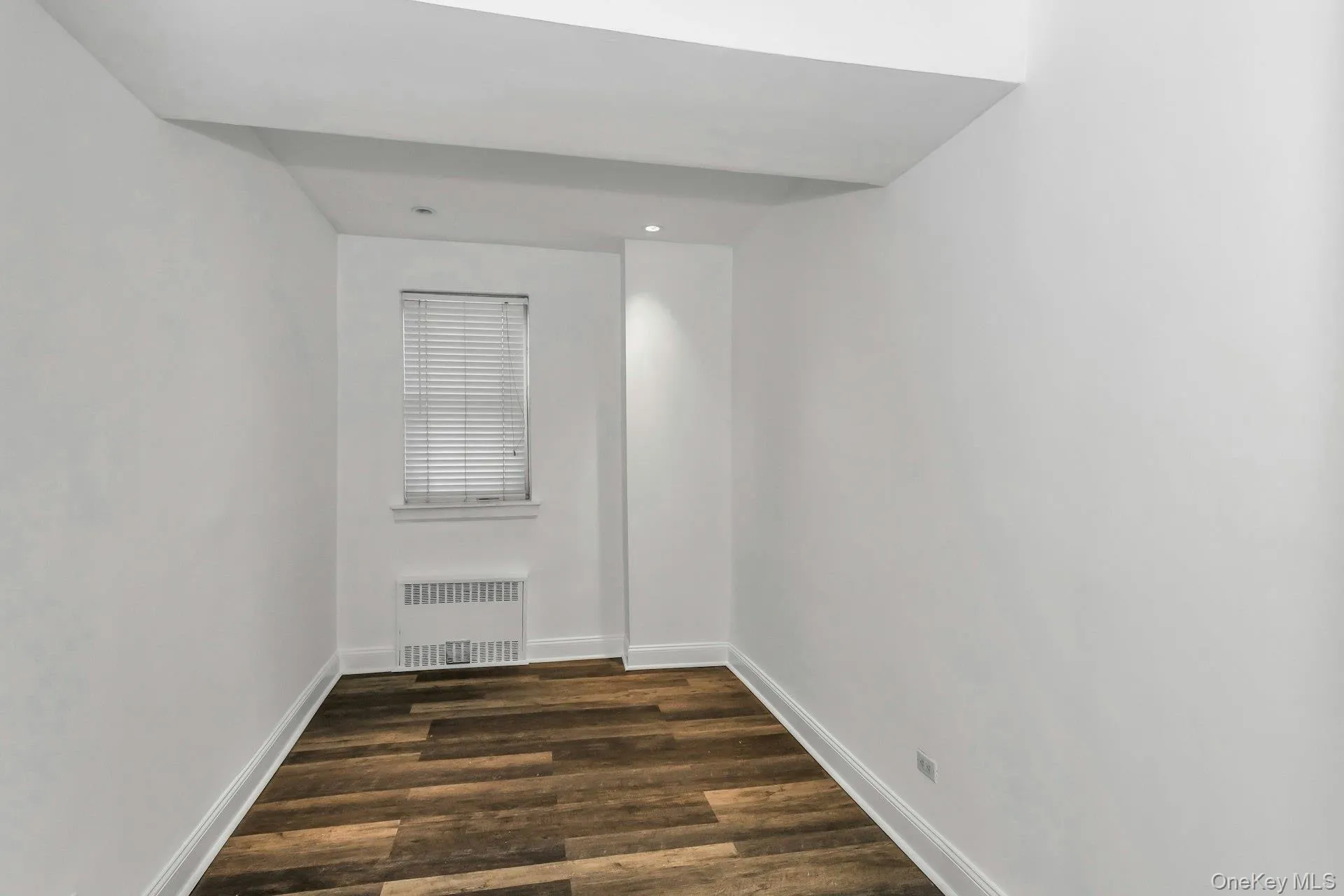 Spare room featuring dark wood-style flooring and radiator heating unit Spare room featuring dark wood-style flooring and radiator heating unit