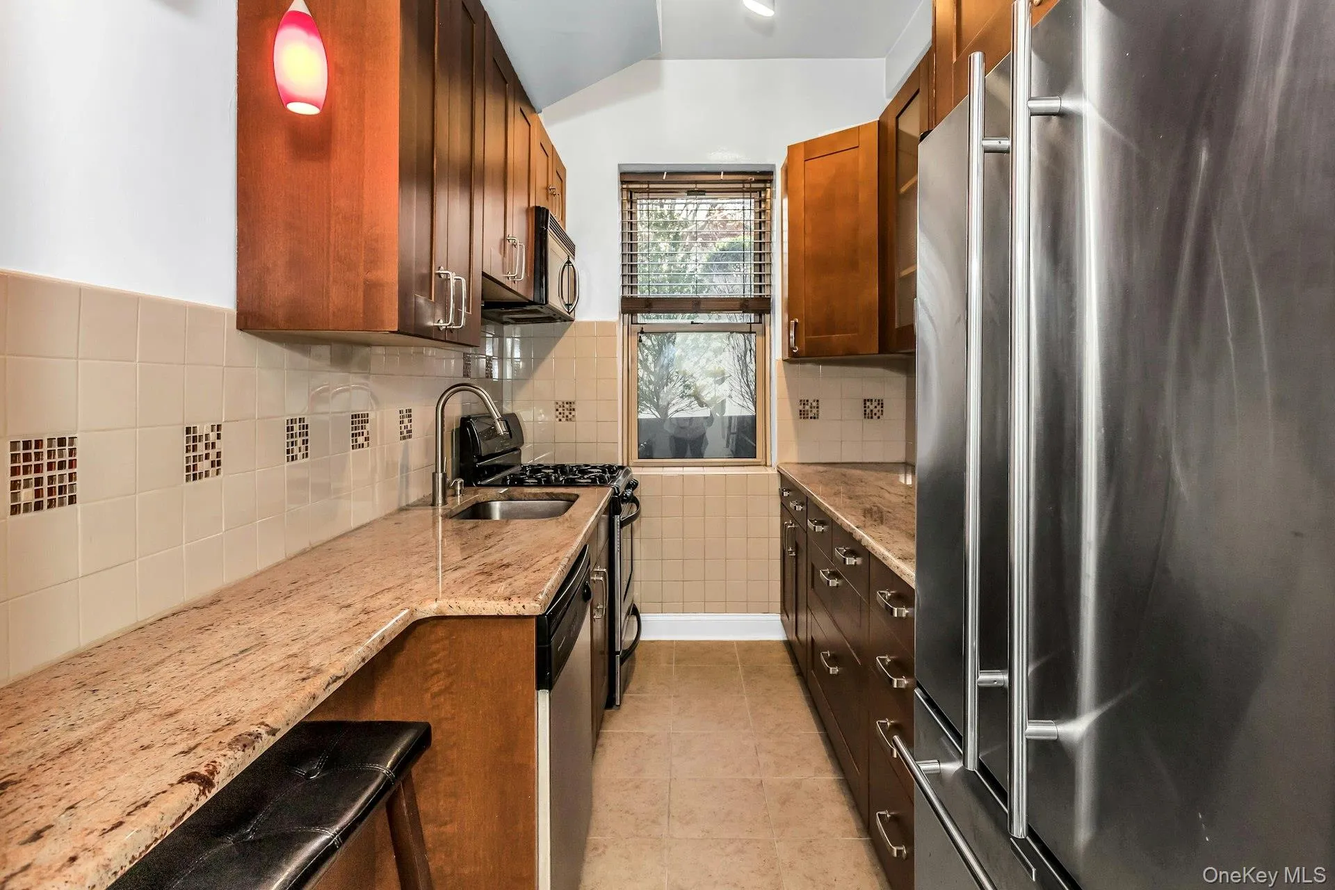 Kitchen featuring appliances with stainless steel finishes, light stone counters, light tile patterned flooring, and backsplash Kitchen featuring appliances with stainless steel finishes, light stone counters, light tile patterned flooring, and backsplash