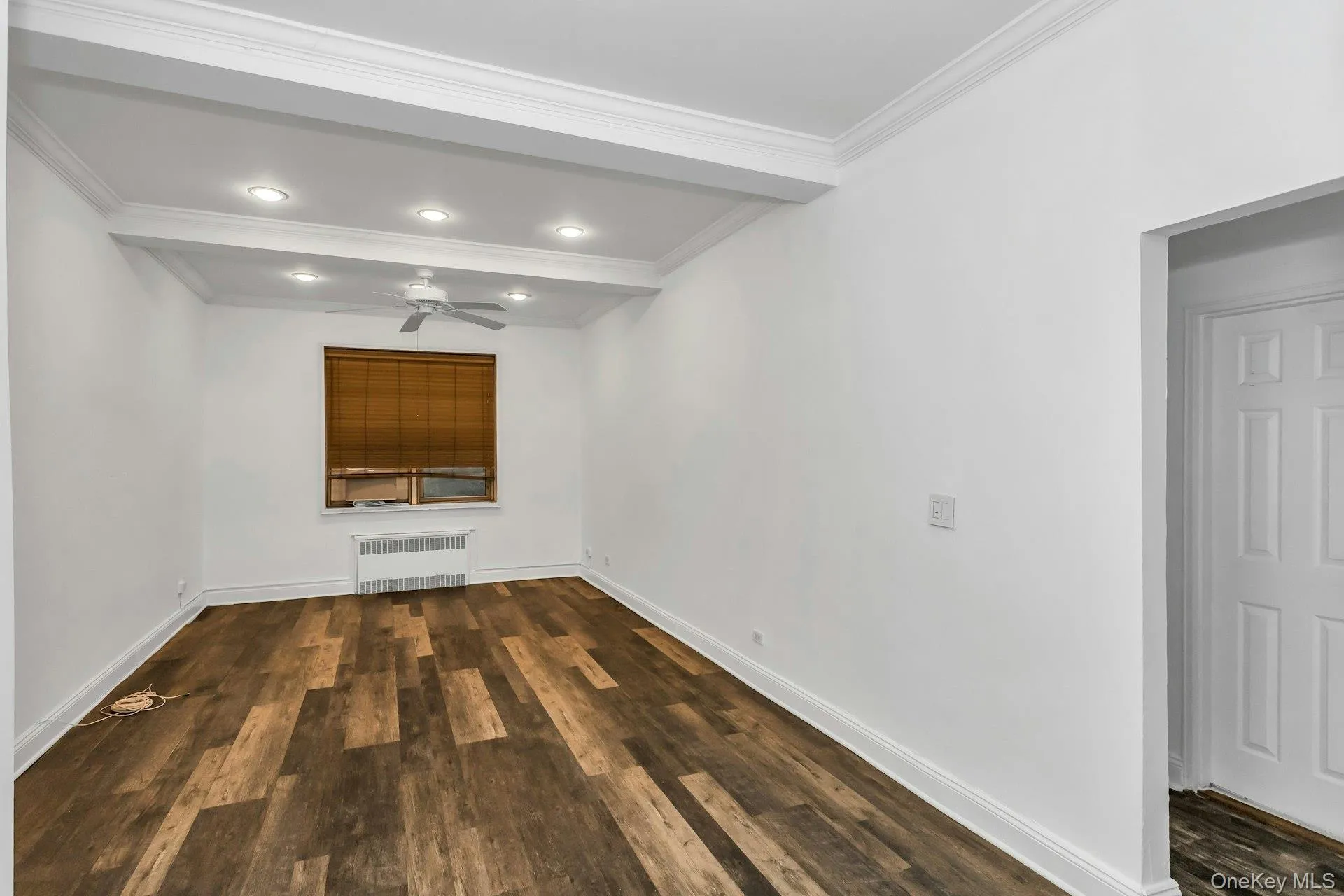 Unfurnished room with dark wood-style floors, radiator, ceiling fan, ornamental molding, and recessed lighting Unfurnished room with dark wood-style floors, radiator, ceiling fan, ornamental molding, and recessed lighting