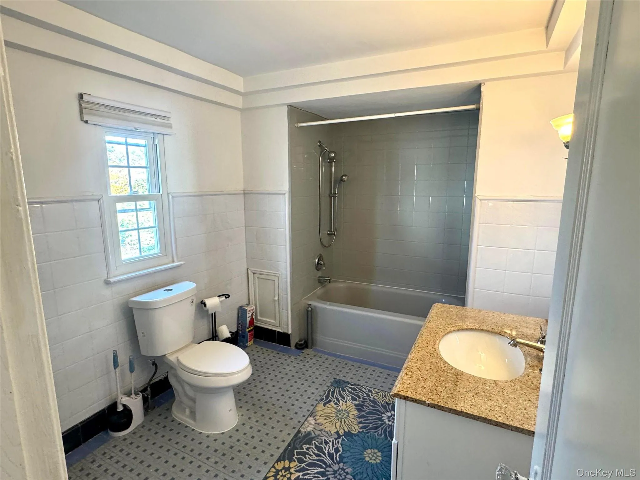 Full bathroom with vanity, tile walls, wainscoting, and bathing tub / shower combination Full bathroom with vanity, tile walls, wainscoting, and bathing tub / shower combination