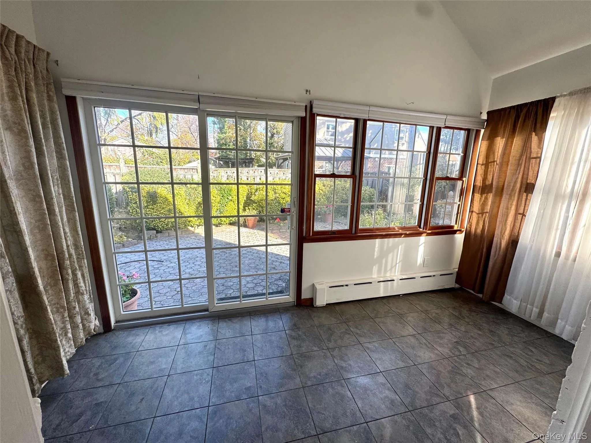 Unfurnished sunroom with baseboard heating and lofted ceiling Unfurnished sunroom with baseboard heating and lofted ceiling