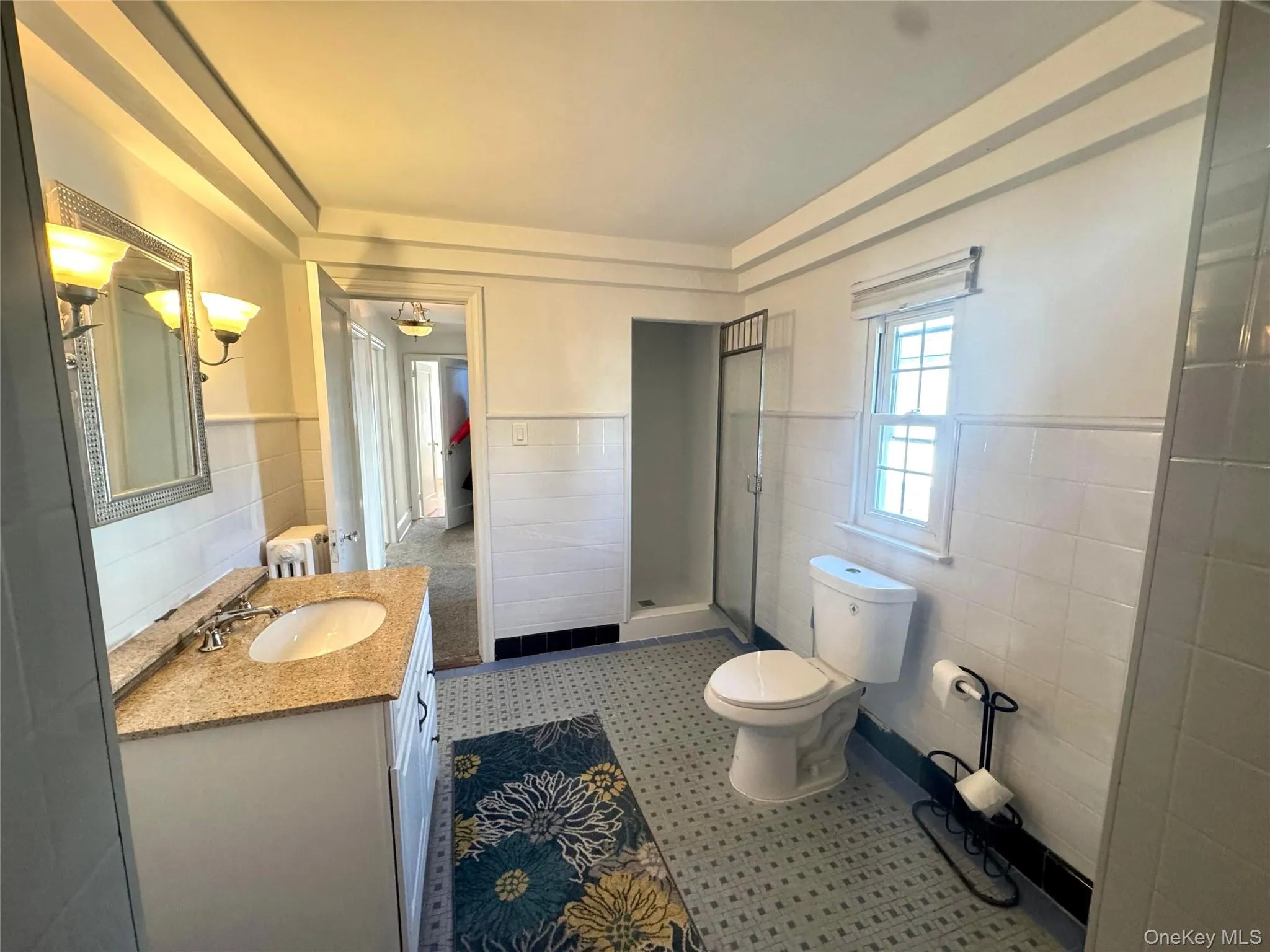 Bathroom with vanity, wainscoting, tile walls, and a shower stall Bathroom with vanity, wainscoting, tile walls, and a shower stall