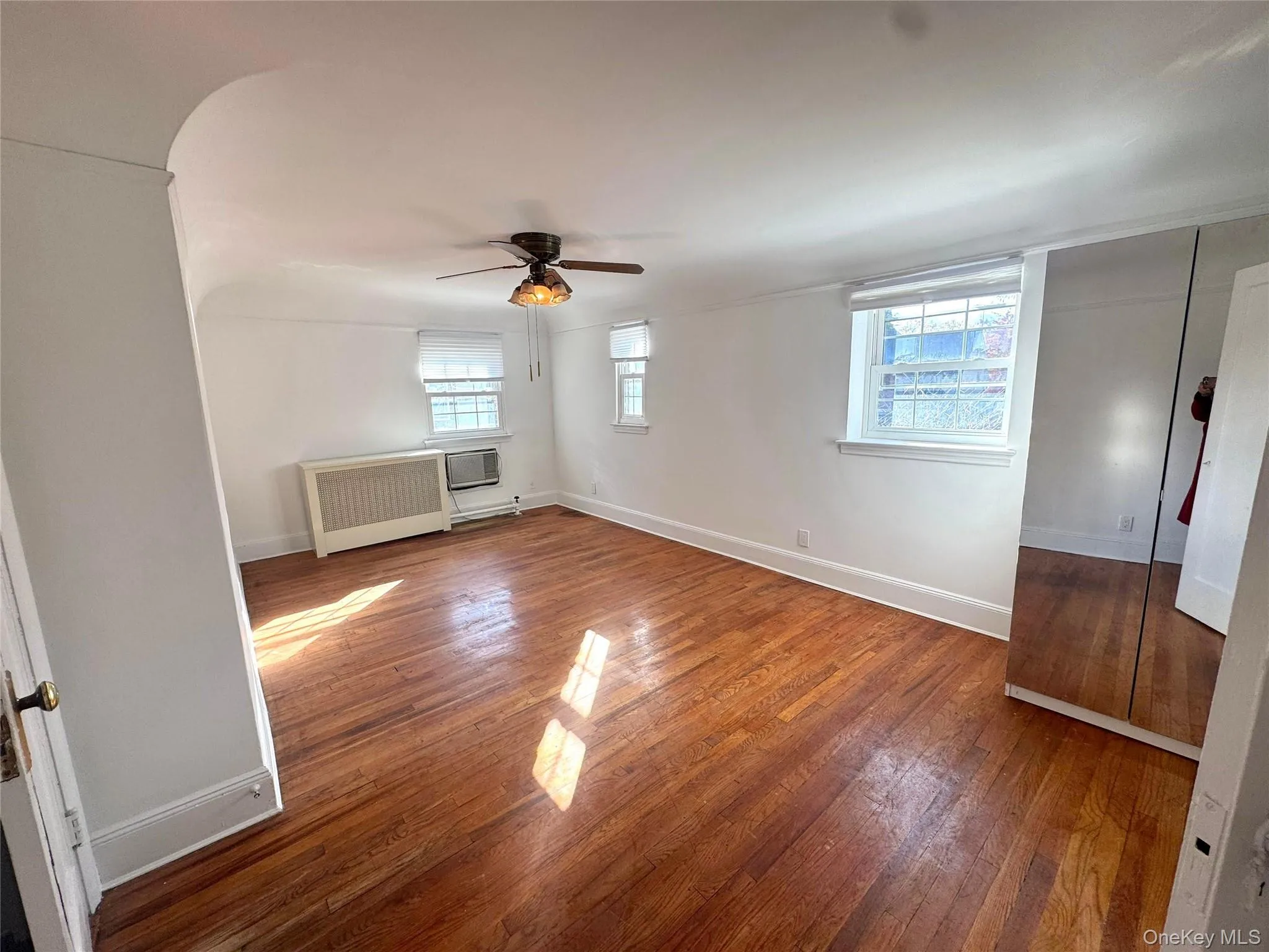 Empty room featuring hardwood / wood-style floors, radiator, and a baseboard radiator Empty room featuring hardwood / wood-style floors, radiator, and a baseboard radiator