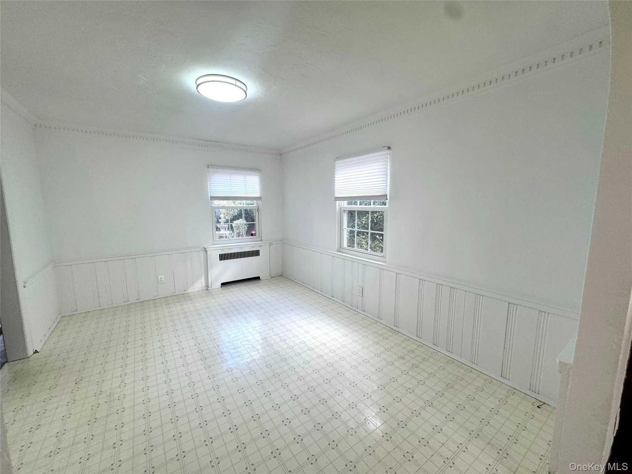 Unfurnished room featuring a wainscoted wall, radiator, a decorative wall, tile patterned floors, and a textured ceiling Unfurnished room featuring a wainscoted wall, radiator, a decorative wall, tile patterned floors, and a textured ceiling