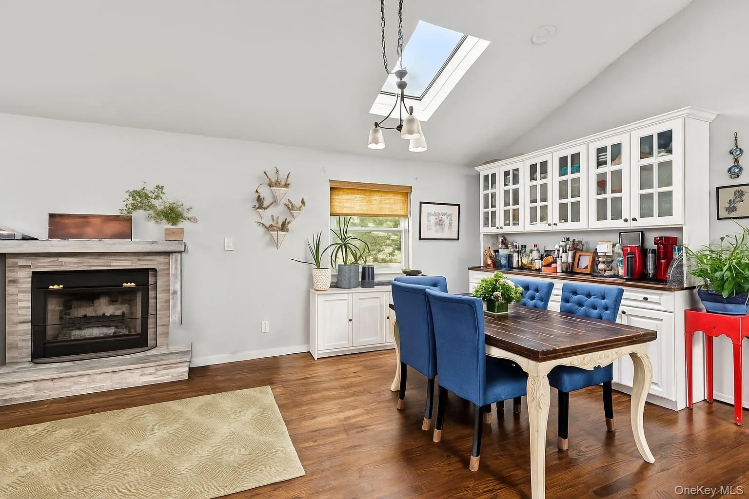 Dining space featuring a skylight, lofted ceiling, dark wood-style flooring, and a fireplace with raised hearth Dining space featuring a skylight, lofted ceiling, dark wood-style flooring, and a fireplace with raised hearth