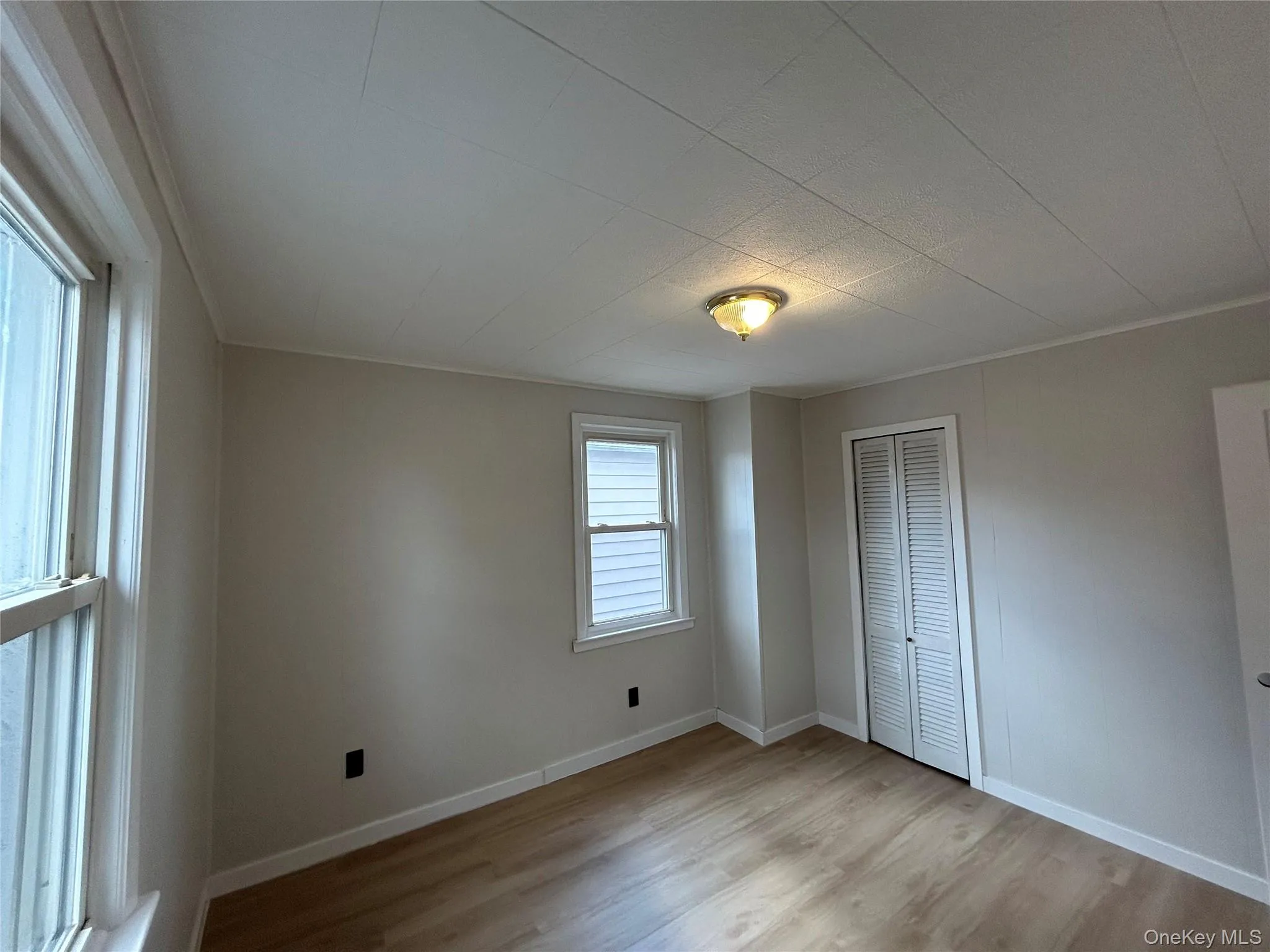 Unfurnished bedroom with light wood finished floors, a closet, and crown molding Unfurnished bedroom with light wood finished floors, a closet, and crown molding