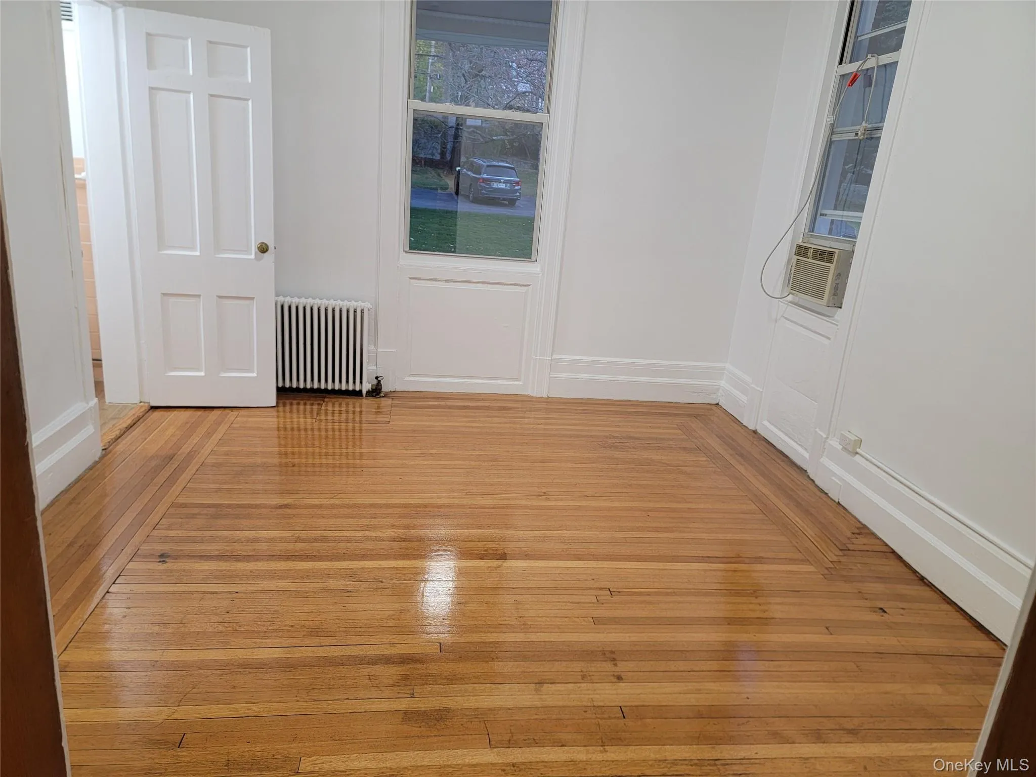 Empty room with radiator heating unit and hardwood / wood-style flooring Empty room with radiator heating unit and hardwood / wood-style flooring