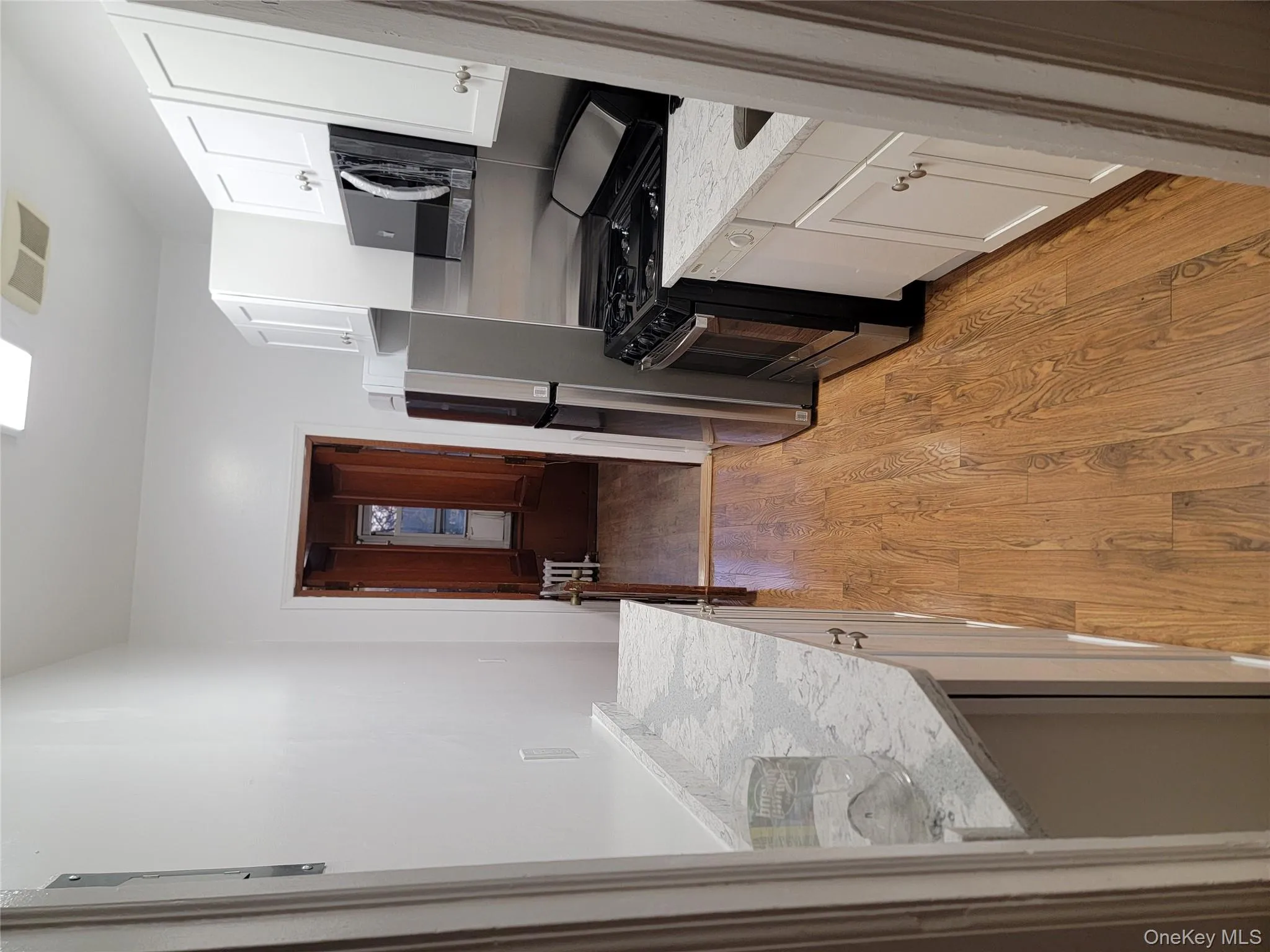 Kitchen featuring range, white cabinets, light wood-type flooring, light stone counters, and fridge Kitchen featuring range, white cabinets, light wood-type flooring, light stone counters, and fridge