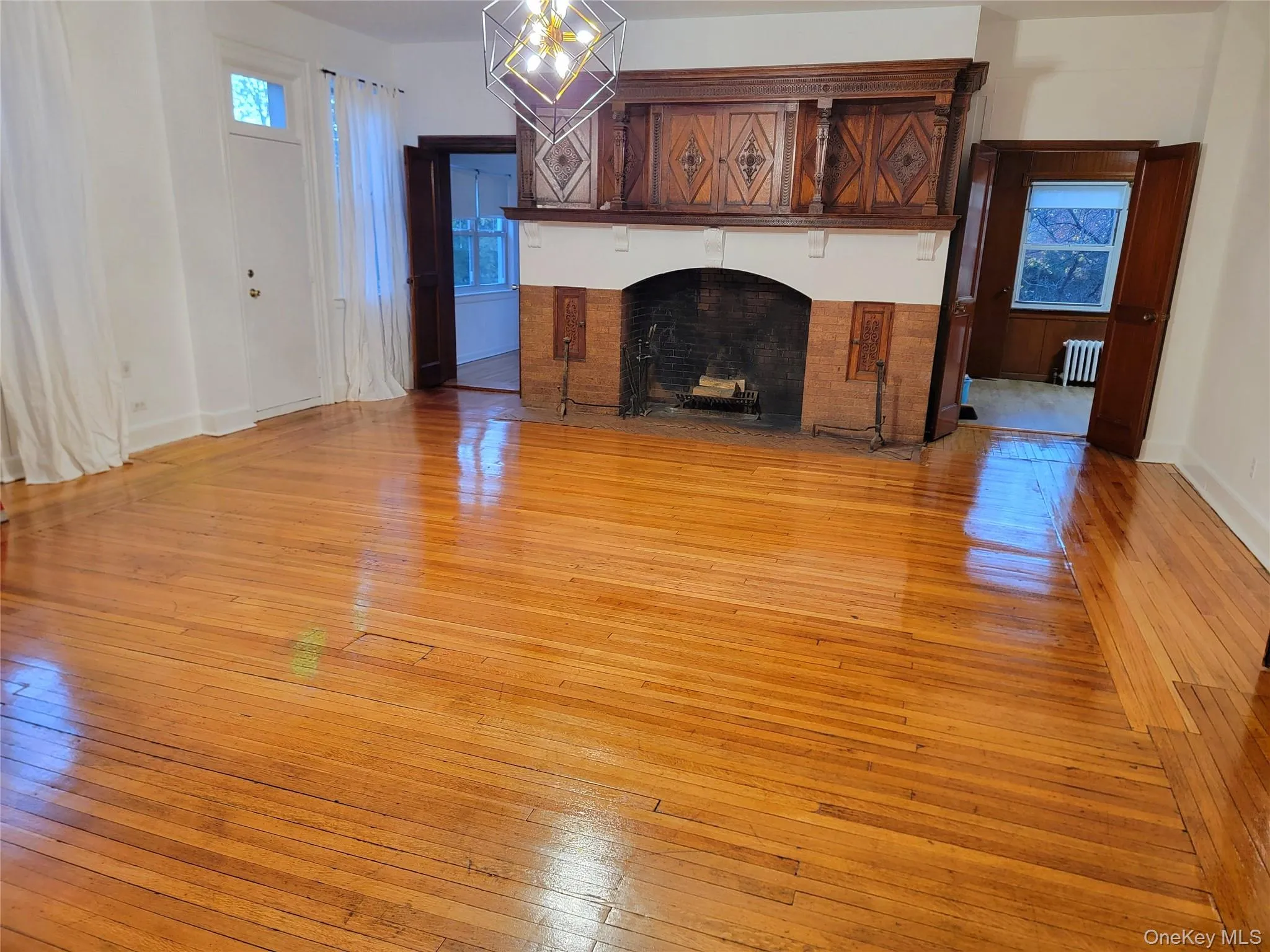 Unfurnished living room with light wood-style flooring, a fireplace, and a chandelier Unfurnished living room with light wood-style flooring, a fireplace, and a chandelier