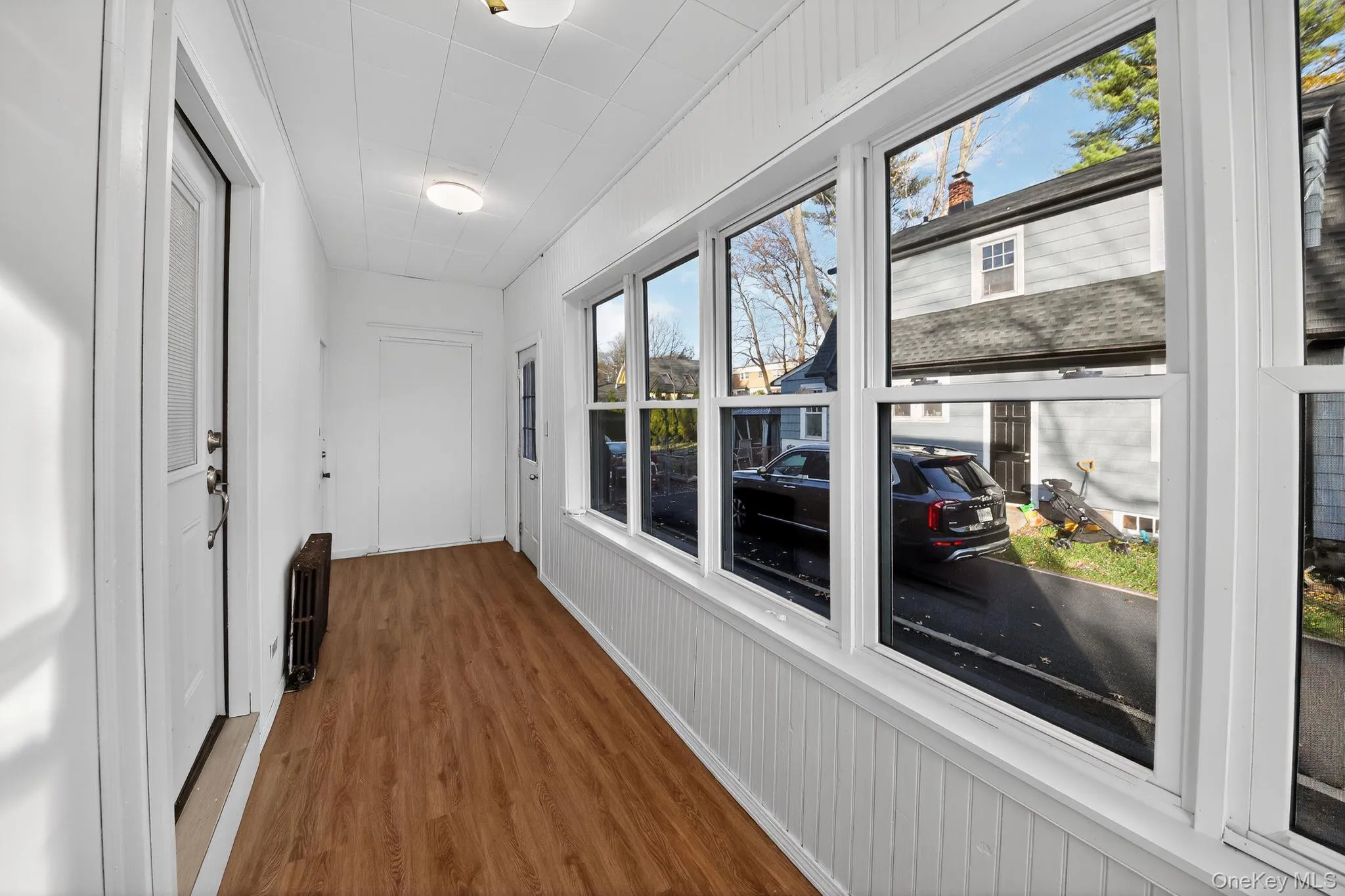 Sunroom featuring wood finished floors and radiator heating unit Sunroom featuring wood finished floors and radiator heating unit