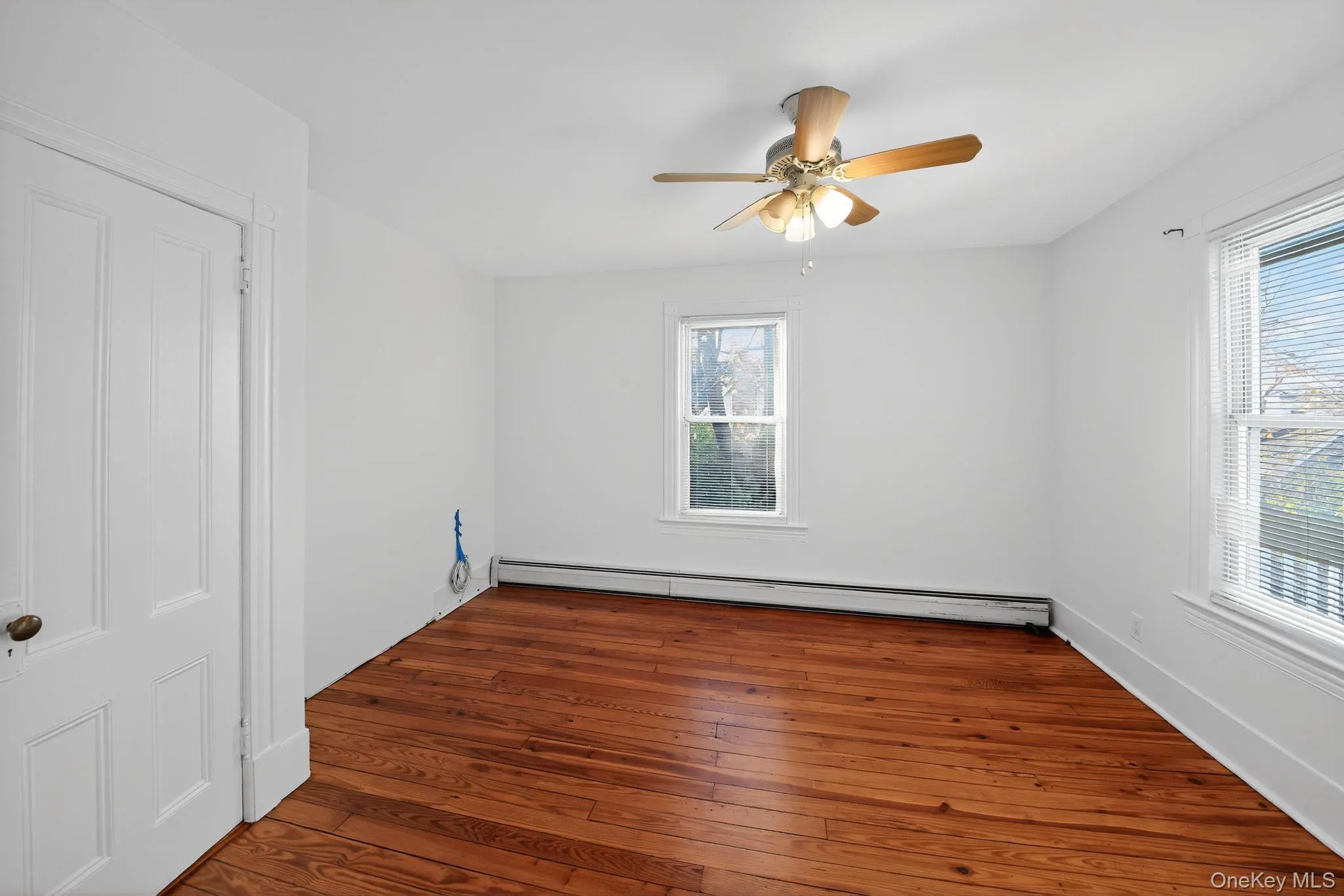Spare room with dark wood-style flooring, a baseboard radiator, and a ceiling fan Spare room with dark wood-style flooring, a baseboard radiator, and a ceiling fan