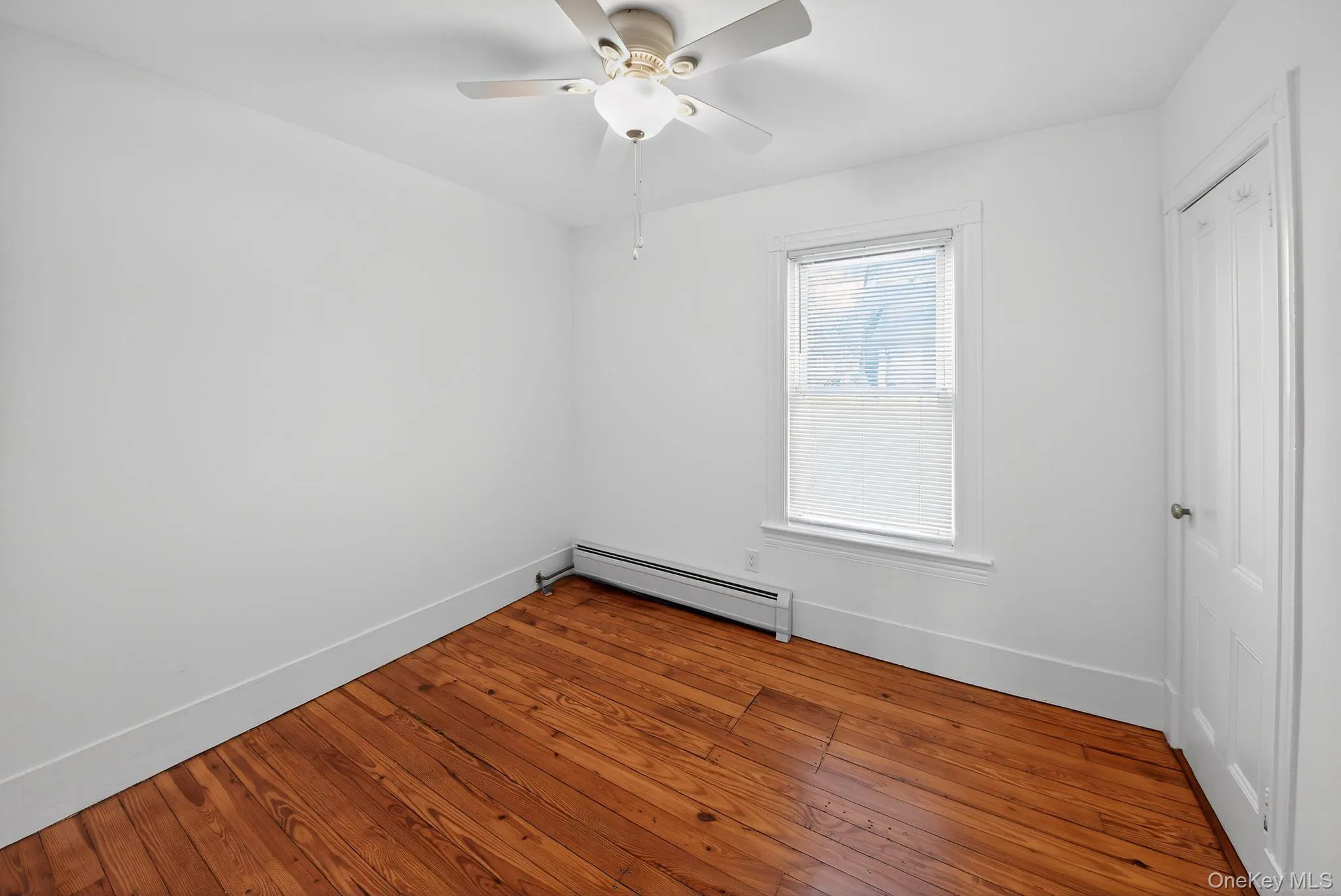 Empty room featuring a baseboard heating unit, hardwood / wood-style floors, and a ceiling fan Empty room featuring a baseboard heating unit, hardwood / wood-style floors, and a ceiling fan