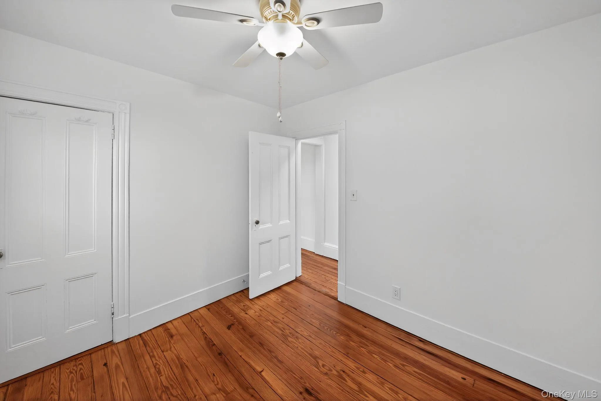 Unfurnished bedroom with a ceiling fan and hardwood / wood-style flooring Unfurnished bedroom with a ceiling fan and hardwood / wood-style flooring