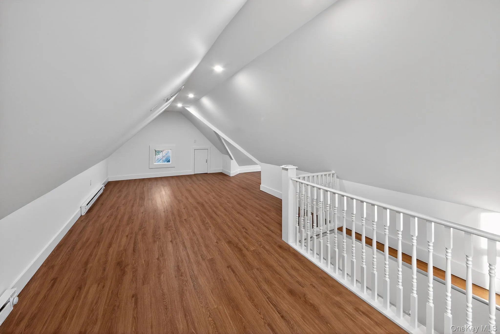 Additional living space featuring wood finished floors, a baseboard heating unit, vaulted ceiling, and recessed lighting Additional living space featuring wood finished floors, a baseboard heating unit, vaulted ceiling, and recessed lighting