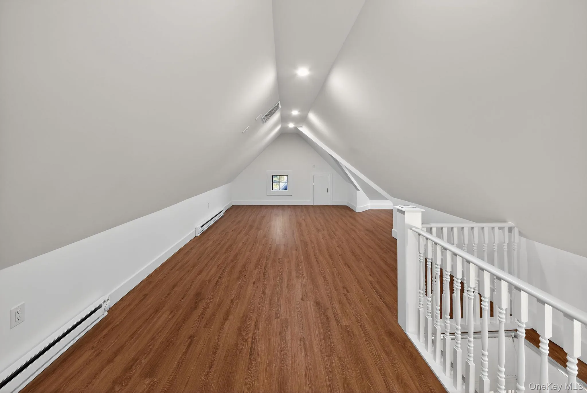 Additional living space with a baseboard radiator, wood finished floors, and vaulted ceiling Additional living space with a baseboard radiator, wood finished floors, and vaulted ceiling