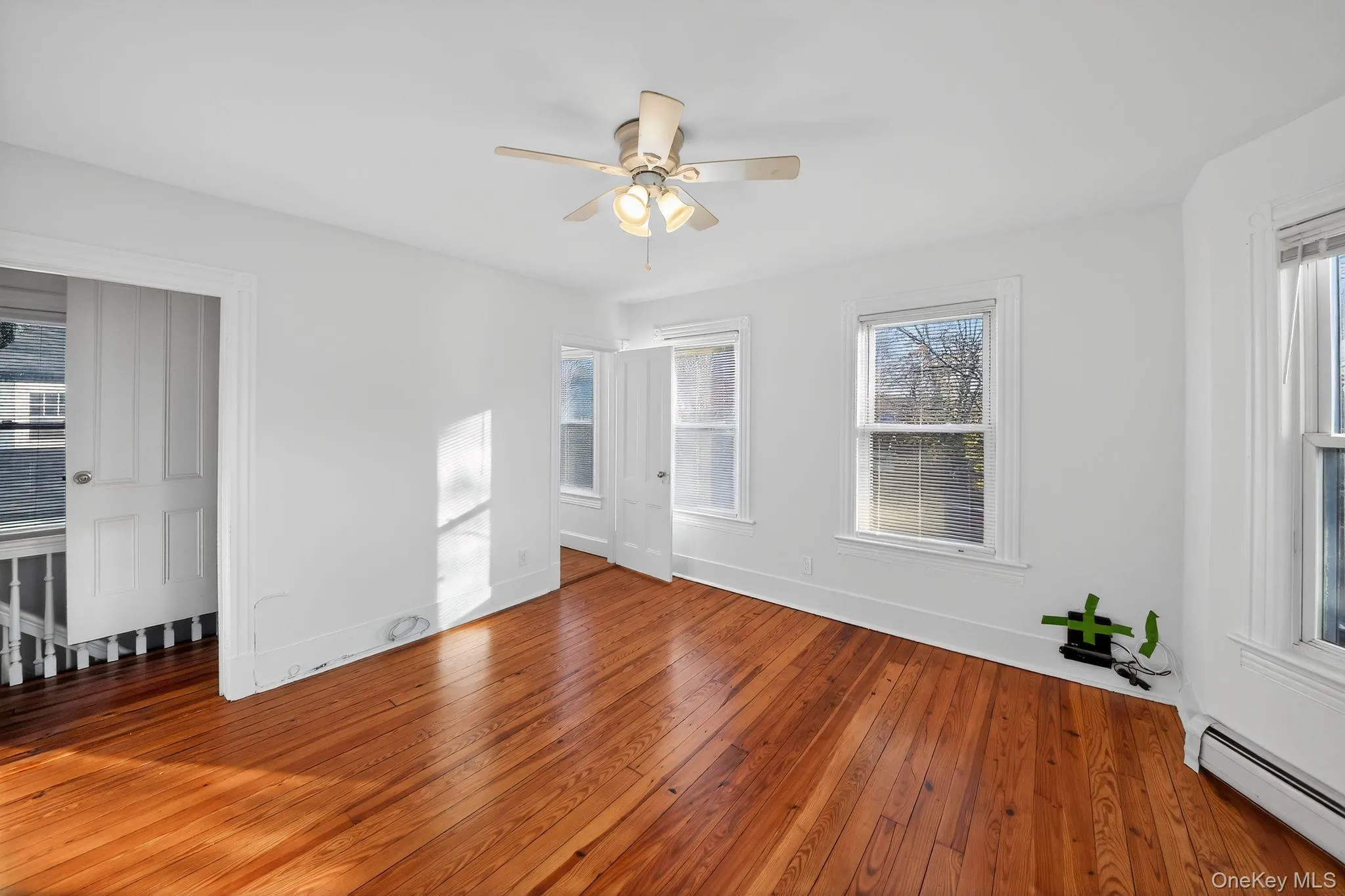 Unfurnished room featuring baseboard heating, hardwood / wood-style floors, and a ceiling fan Unfurnished room featuring baseboard heating, hardwood / wood-style floors, and a ceiling fan