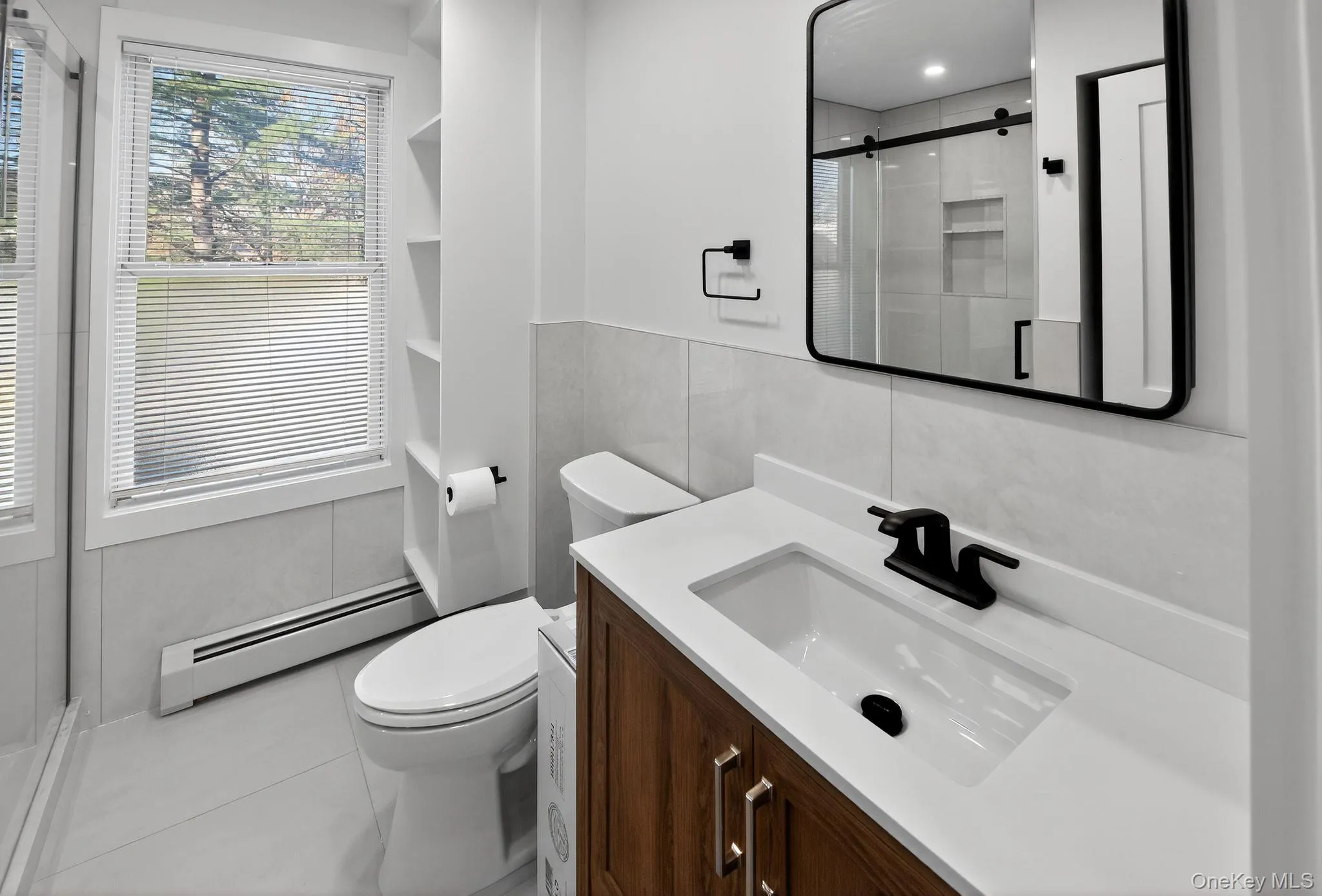 Bathroom featuring a baseboard heating unit, vanity, a shower stall, tile walls, and tile patterned floors Bathroom featuring a baseboard heating unit, vanity, a shower stall, tile walls, and tile patterned floors