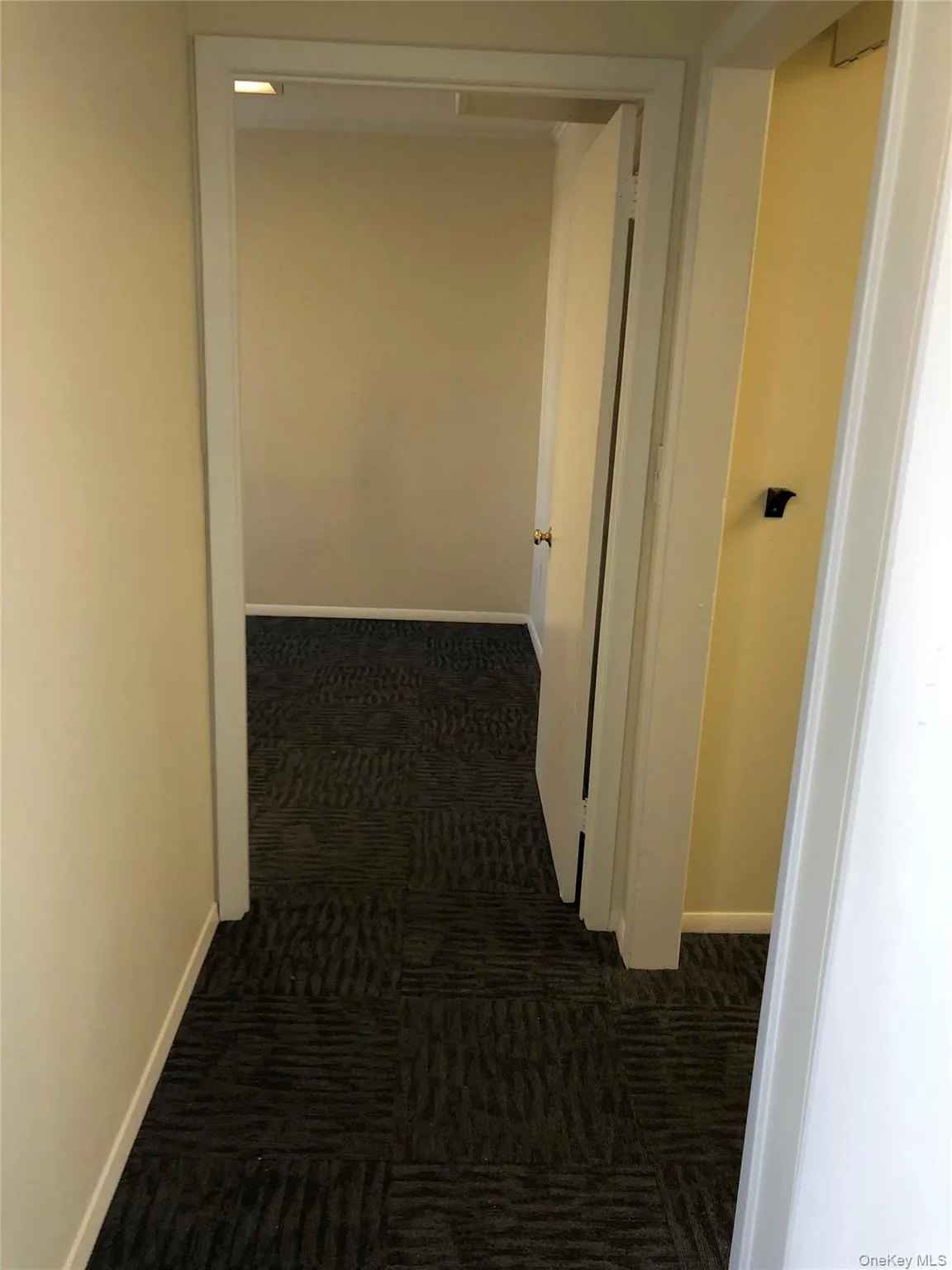 Corridor featuring dark carpet and baseboards Corridor featuring dark carpet and baseboards