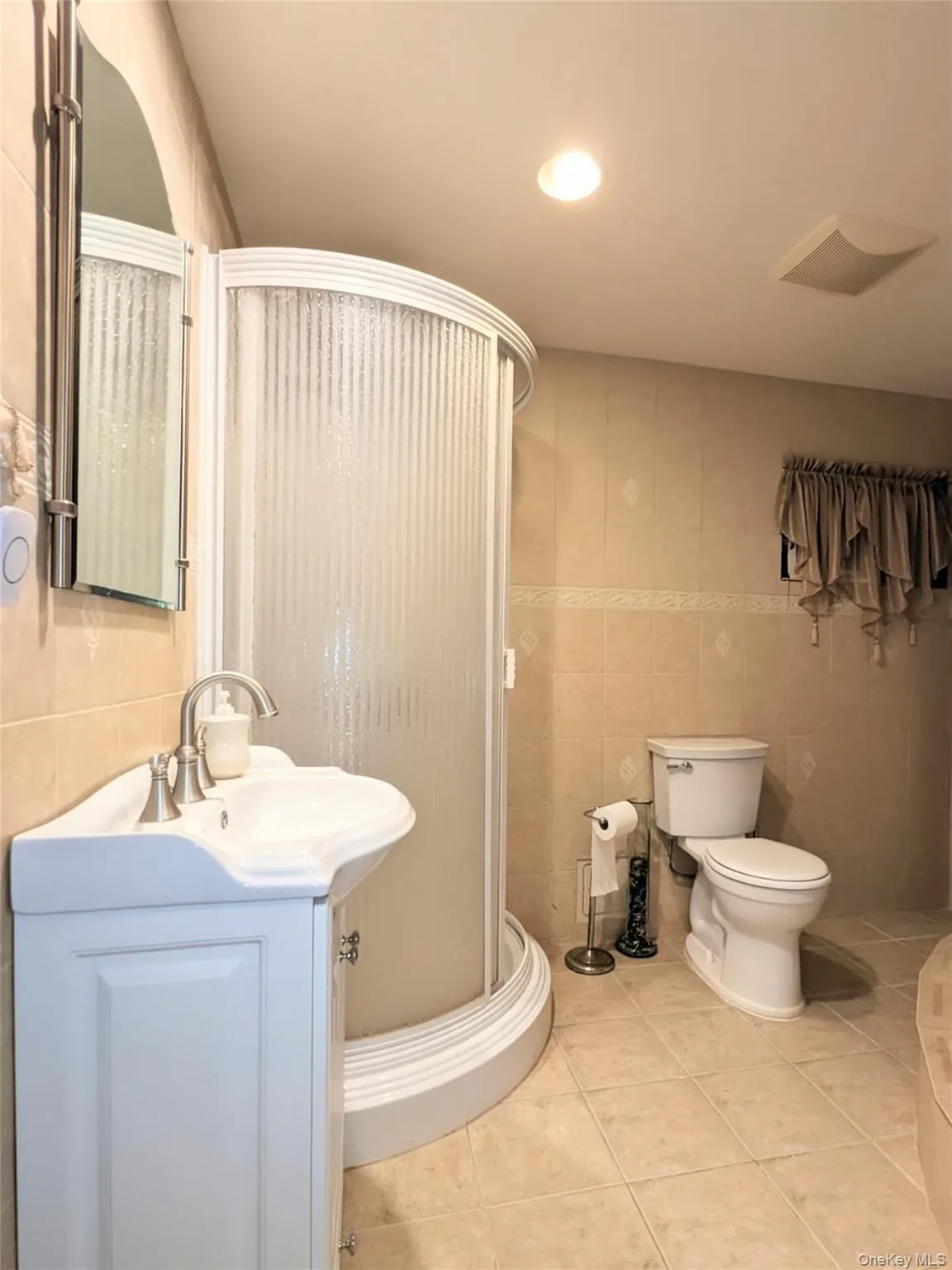 Full bath with vanity, tile walls, light tile patterned flooring, a stall shower, and recessed lighting Full bath with vanity, tile walls, light tile patterned flooring, a stall shower, and recessed lighting