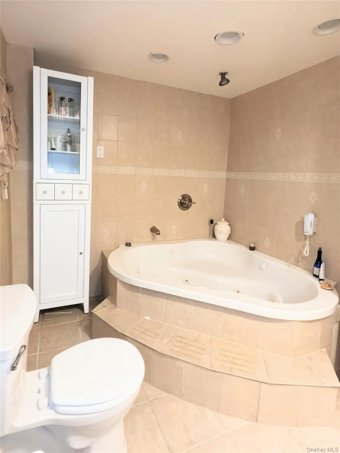 Full bathroom featuring a jetted tub, tile patterned floors, and tile walls Full bathroom featuring a jetted tub, tile patterned floors, and tile walls