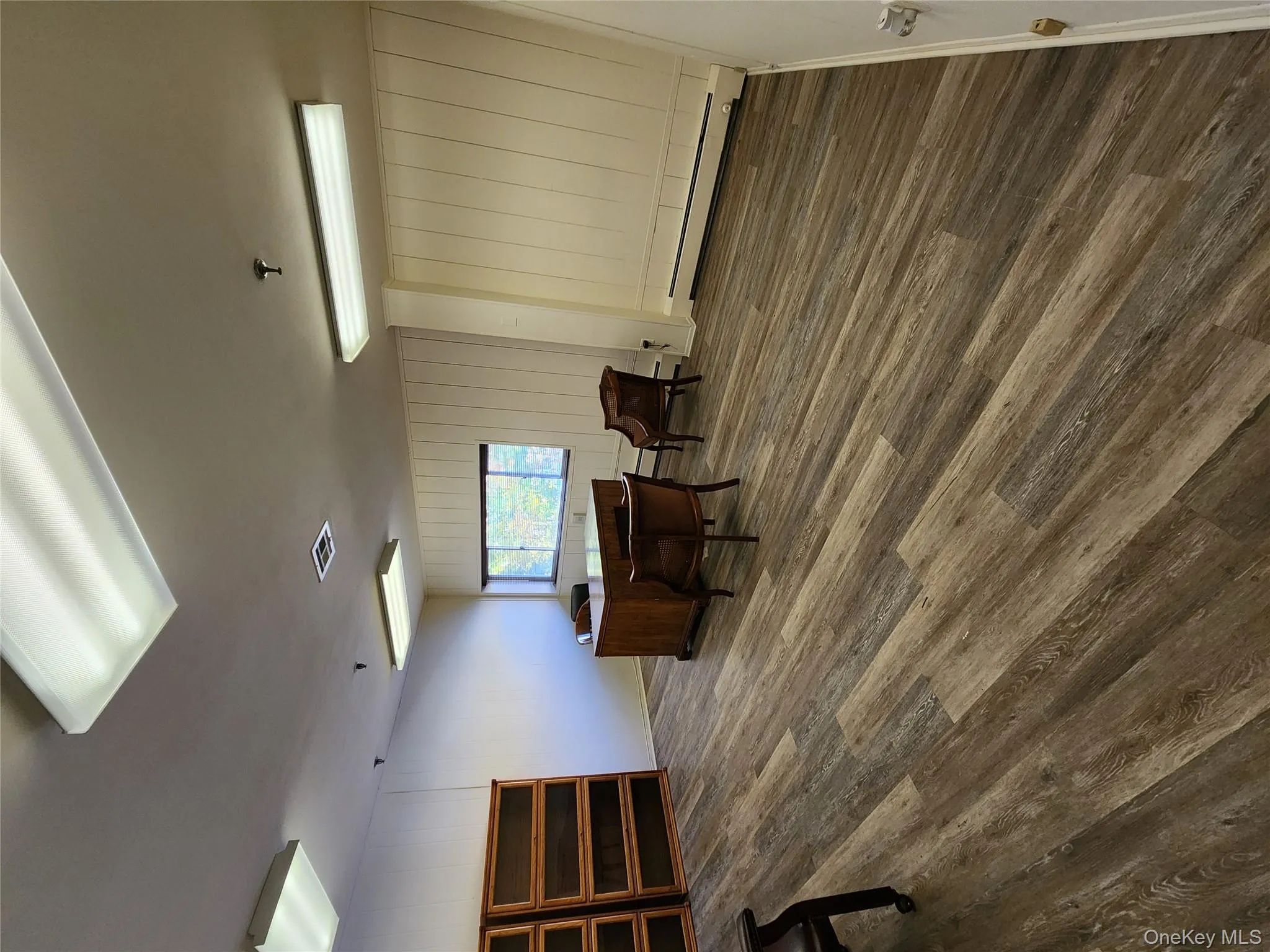 Home office featuring dark wood finished floors, a baseboard radiator, and wooden walls Home office featuring dark wood finished floors, a baseboard radiator, and wooden walls
