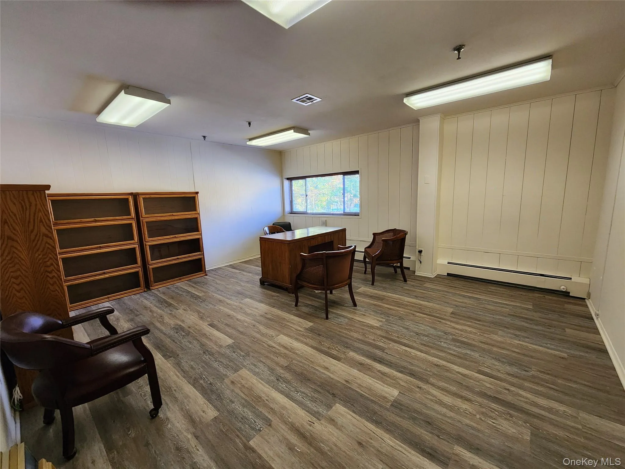 Office with dark wood-style flooring and a baseboard heating unit Office with dark wood-style flooring and a baseboard heating unit